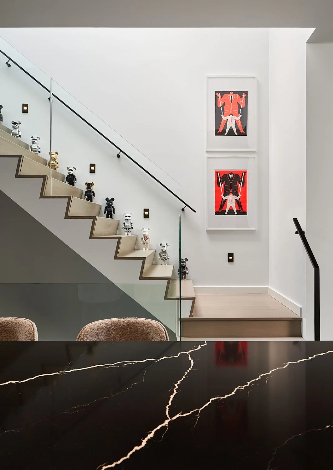 Romeo’s House interior staircase in Etobicoke, Toronto, built by Maxamin Homes, decorated with colorful bear figurines, framed artwork, and black handrail.