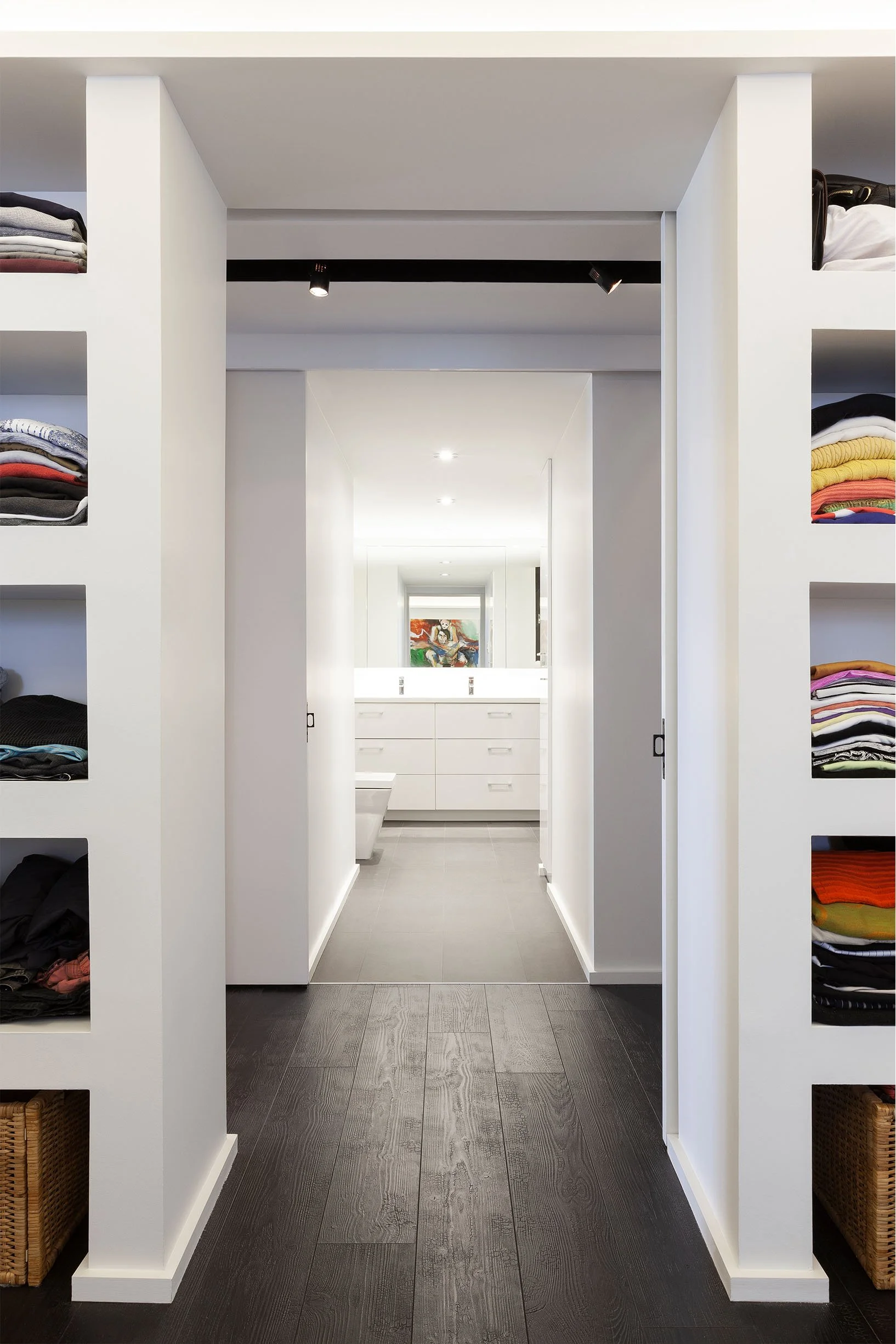 DOHA Nest walk-in closet in North York, Toronto, built by Maxamin Homes, with shelving, white walls, and view into bright bathroom with artwork.