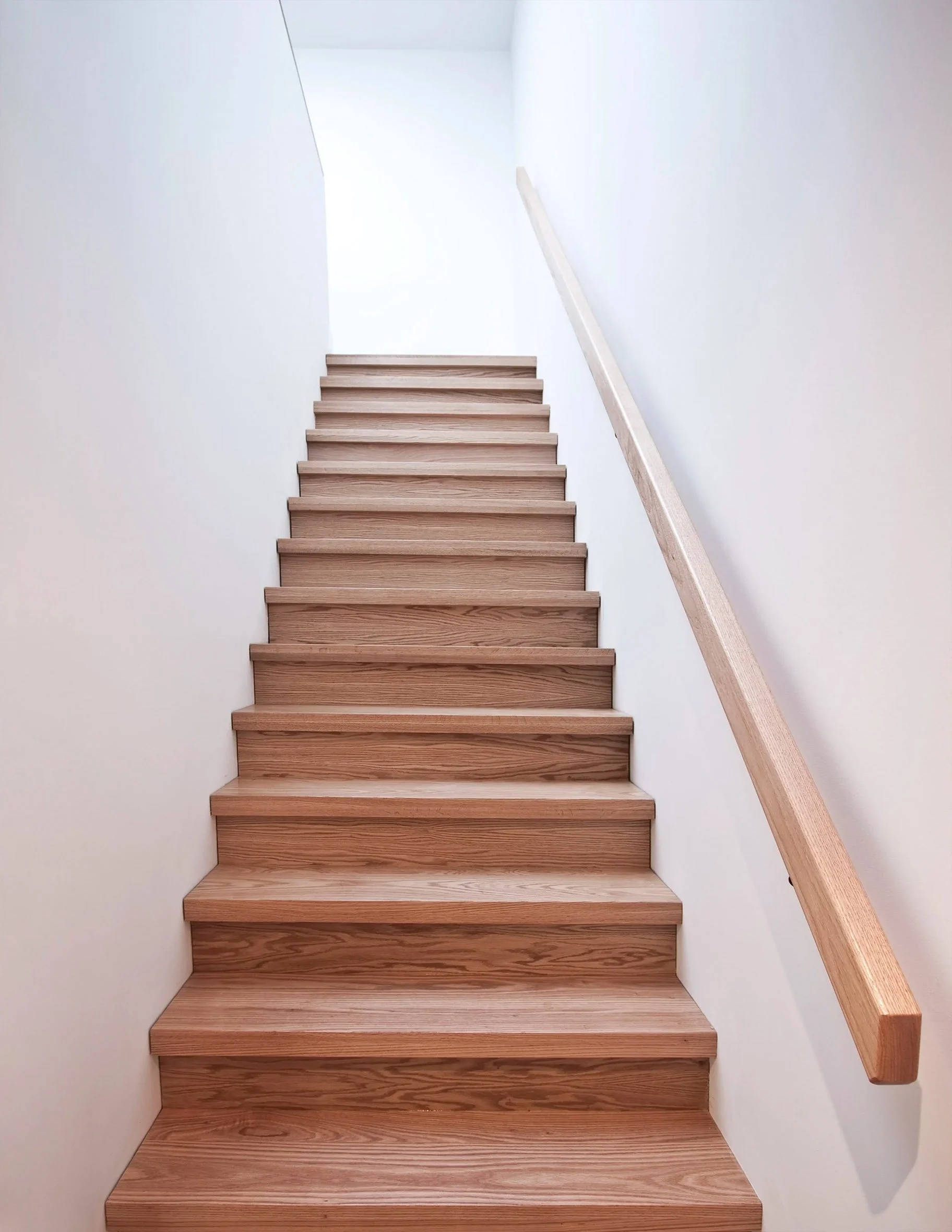 63˚ House interior staircase in East York, Toronto, built by Maxamin Homes, with wooden steps, single handrail, and bright white-walled design.
