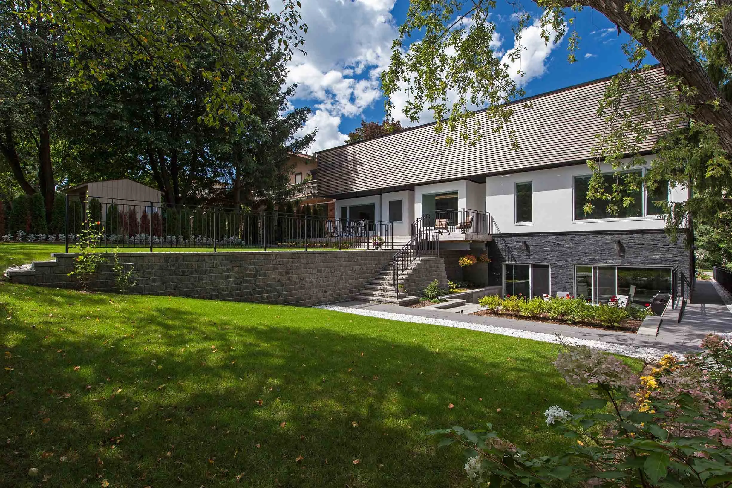Gallery House exterior in East York, Toronto, built by Maxamin Homes, with white and black design, multi-level patio, and lawn with trees.