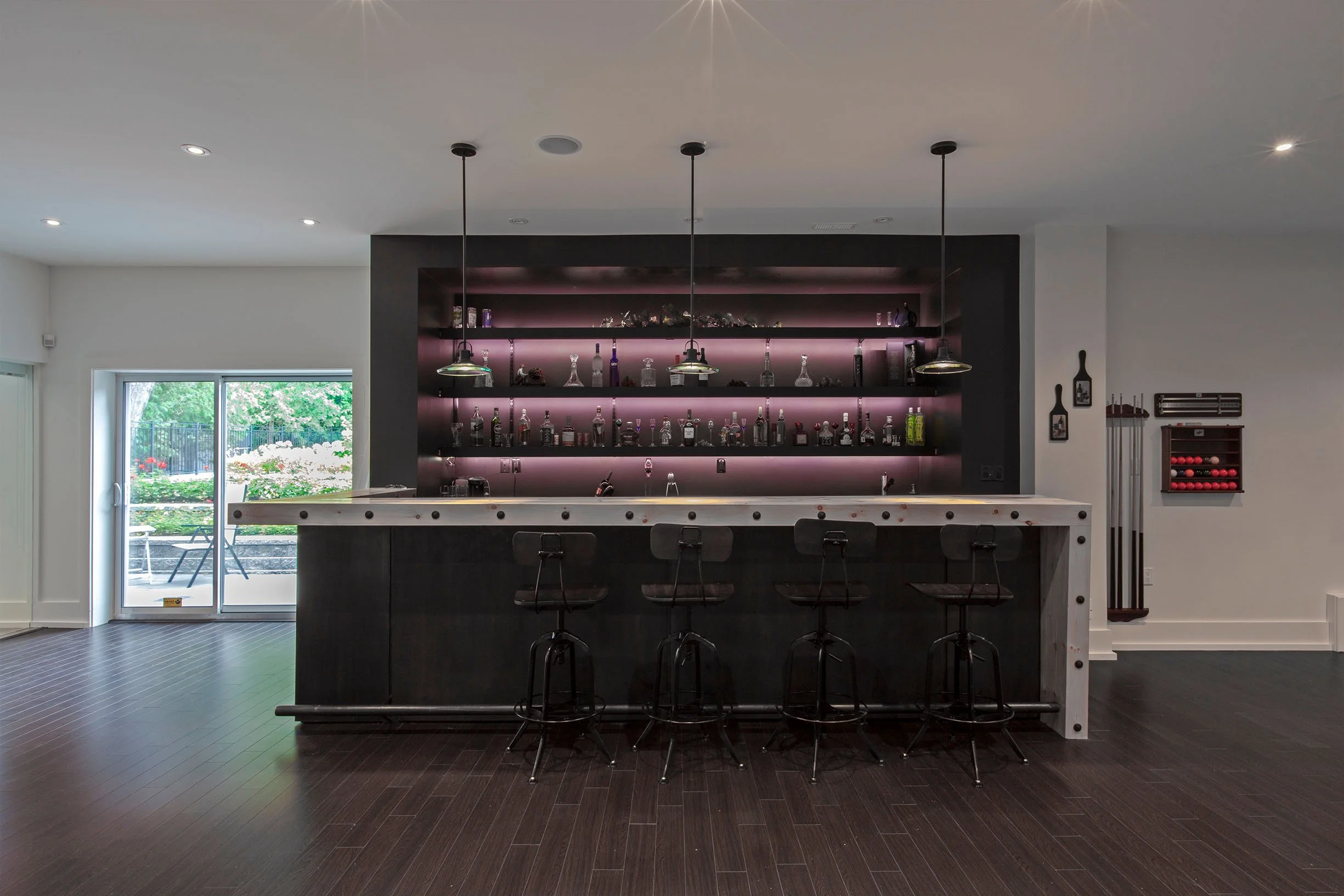 Gallery House bar area in East York, Toronto, built by Maxamin Homes, with black shelving, pink LED lighting, marble countertop, and patio access.