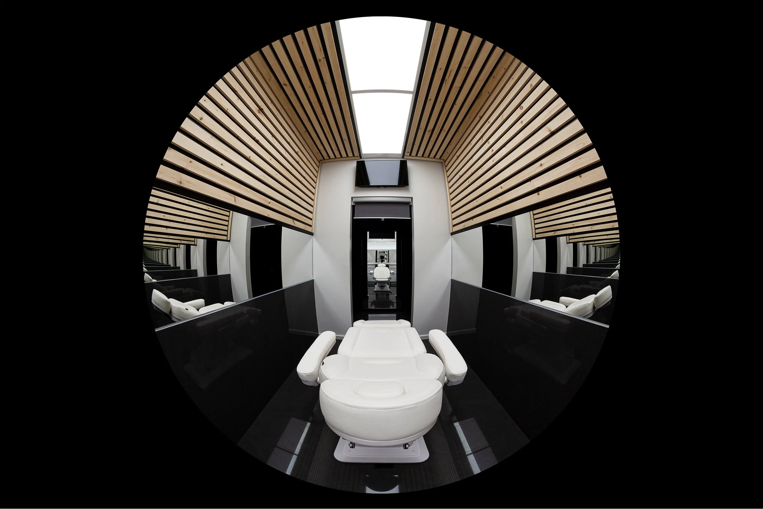 AK Clinic treatment room in Brampton, Toronto, built by Maxamin Homes, featuring futuristic white dentist chair, wood ceiling panels, and black walls.
