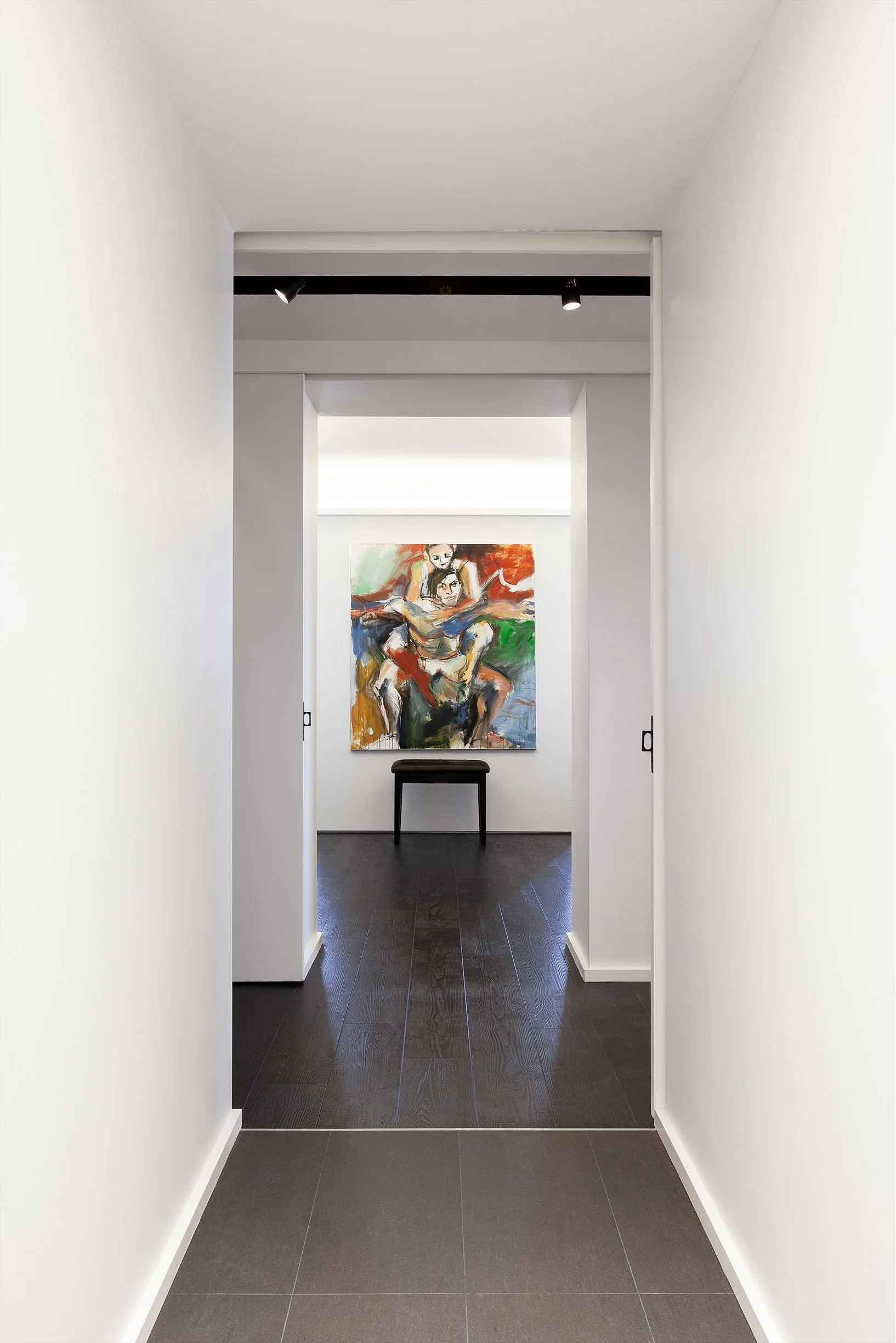 DOHA Nest interior hallway in North York, Toronto, built by Maxamin Homes, leading to gallery with colorful abstract art and a small black stool.