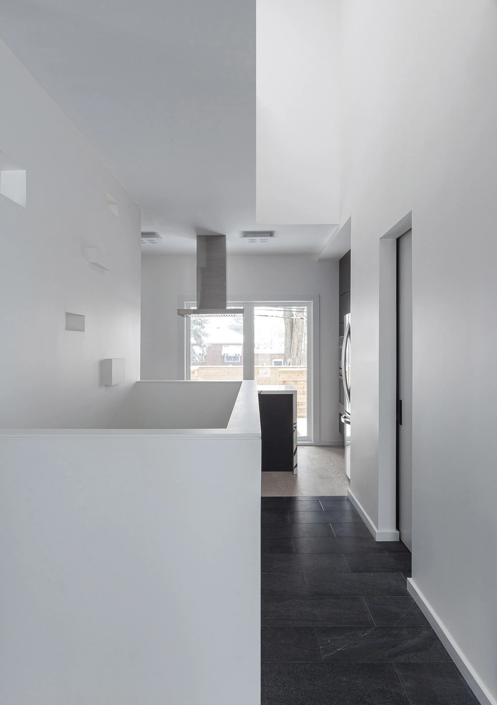 Albers House interior in Scarborough, Toronto, built by Maxamin Homes, minimalist design with sliding glass door, gray walls, and dark flooring.