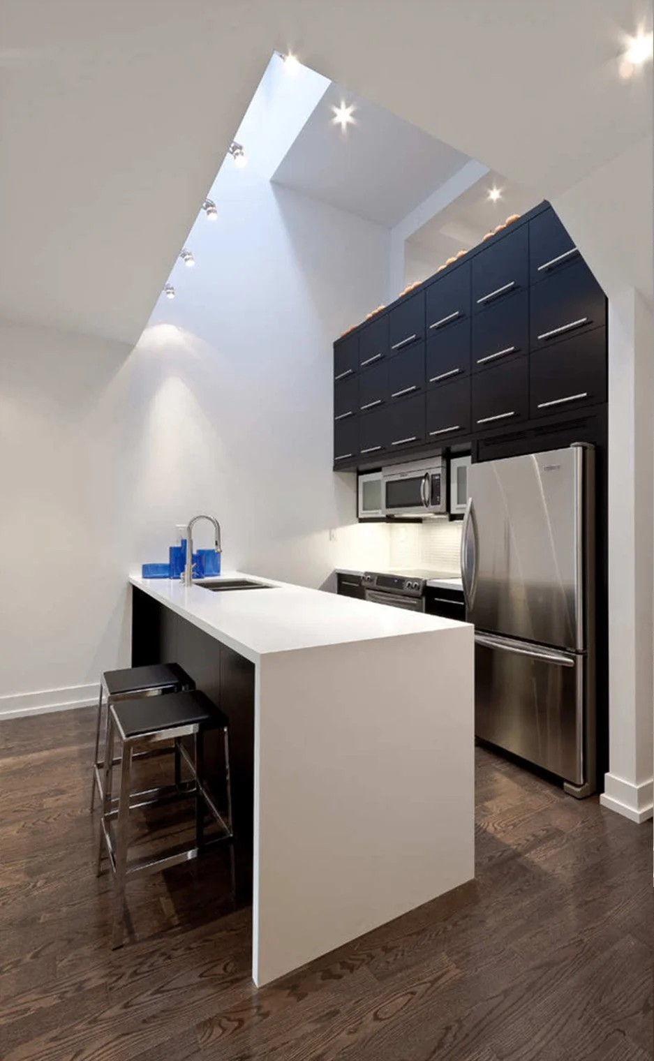 Charcoal House kitchen and dining area in East York, Toronto, built by Maxamin Homes, with black cabinetry, and white countertop.