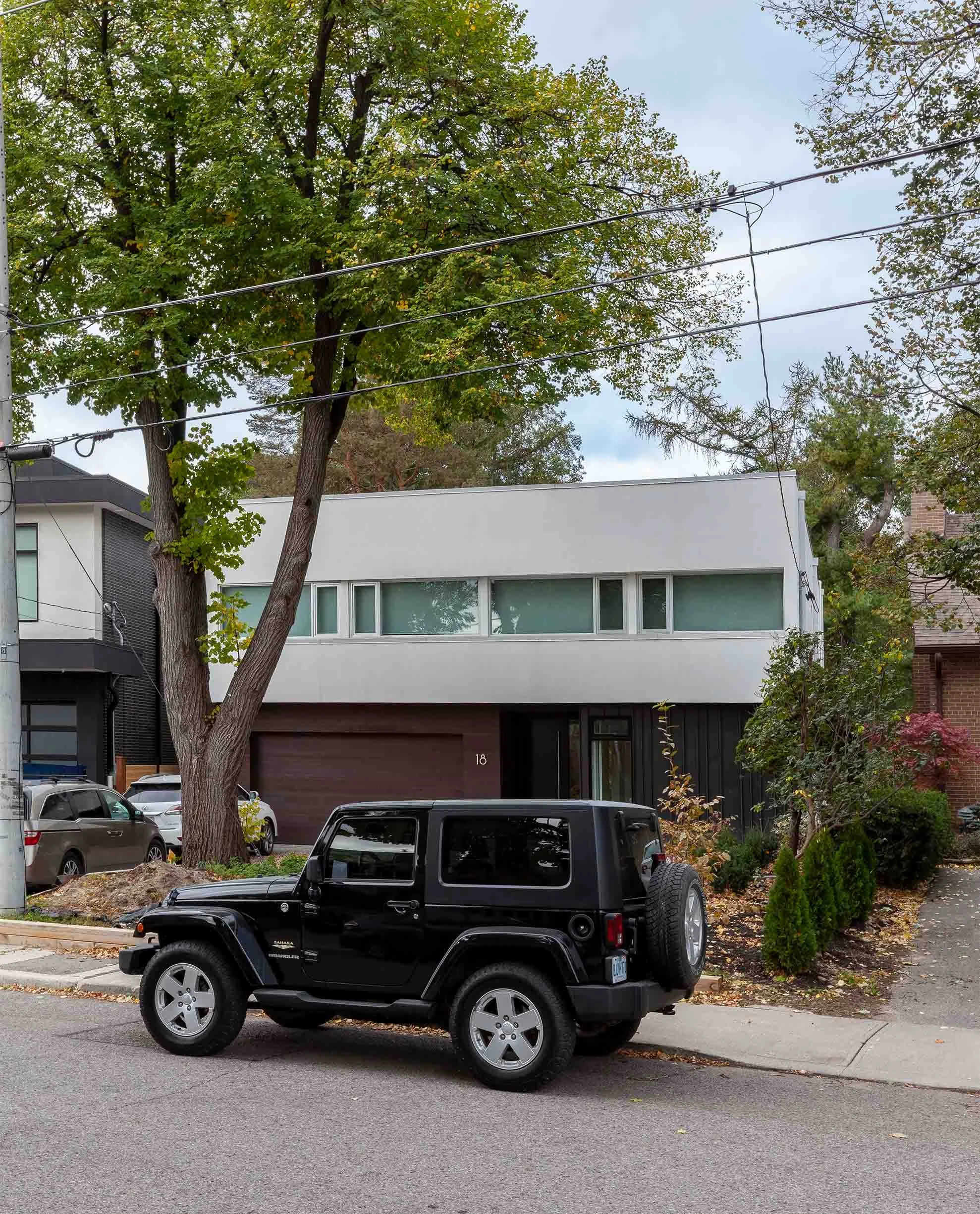 Fun House exterior in East York, Toronto, built by Maxamin Homes, modern white two-story design with large windows and dark garage door on suburban street.