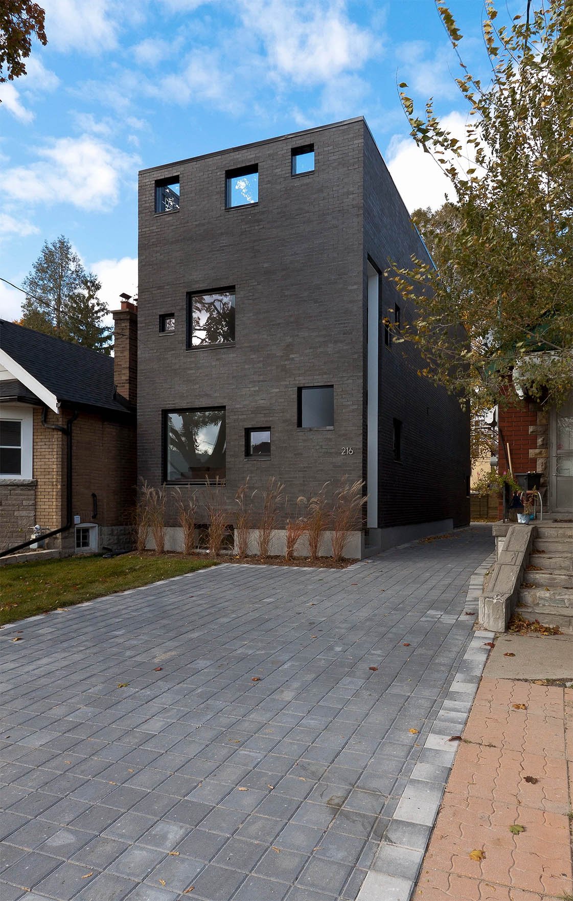 Charcoal House exterior in East York, Toronto, built by Maxamin Homes, four-story dark brick design with multiple windows and paved driveway.