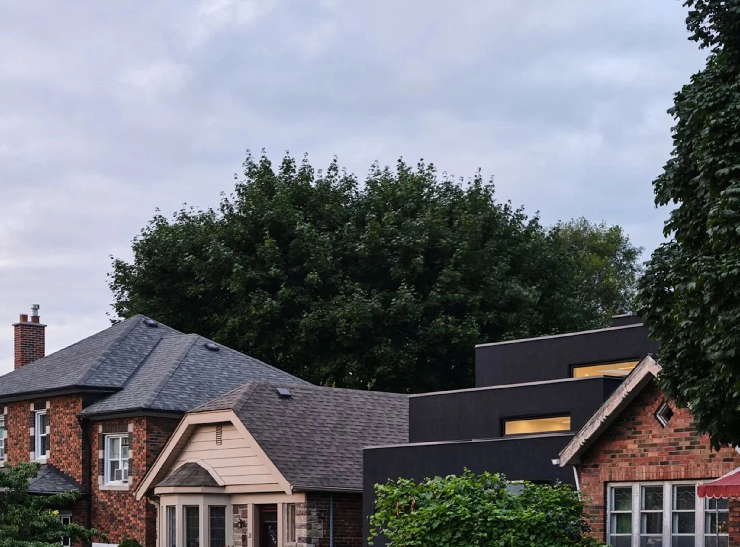 Neighborhood scene near Periscope House in East York, Toronto, featuring modern and traditional homes, trees, and overcast sky.