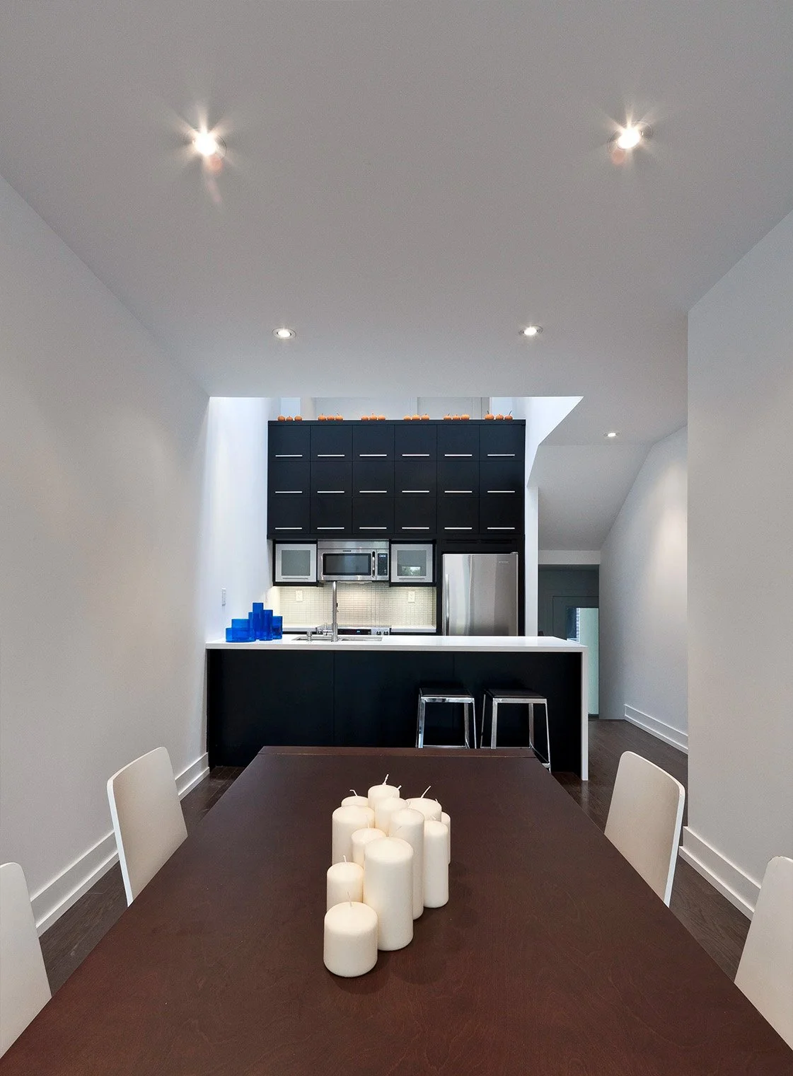 Charcoal House kitchen and dining area in East York, Toronto, built by Maxamin Homes, with dark wood table, black cabinetry, and white countertop.