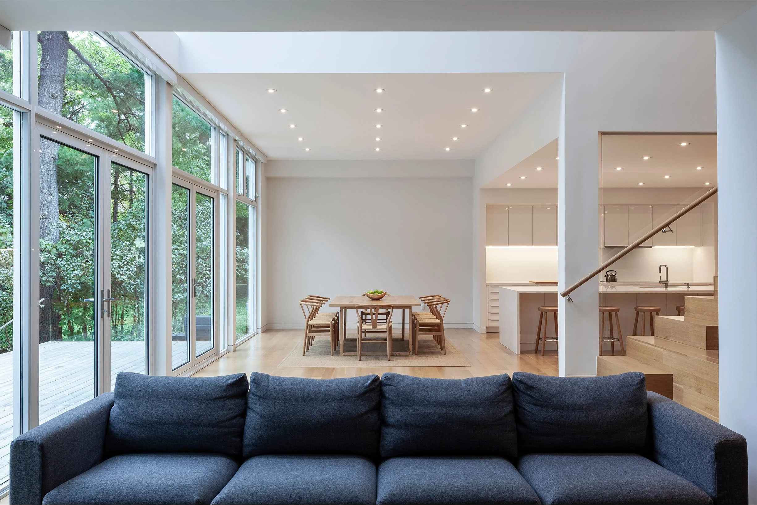 Fun House open-concept interior in East York, Toronto, built by Maxamin Homes, with kitchen, dining, and living areas opening to tree views outside.
