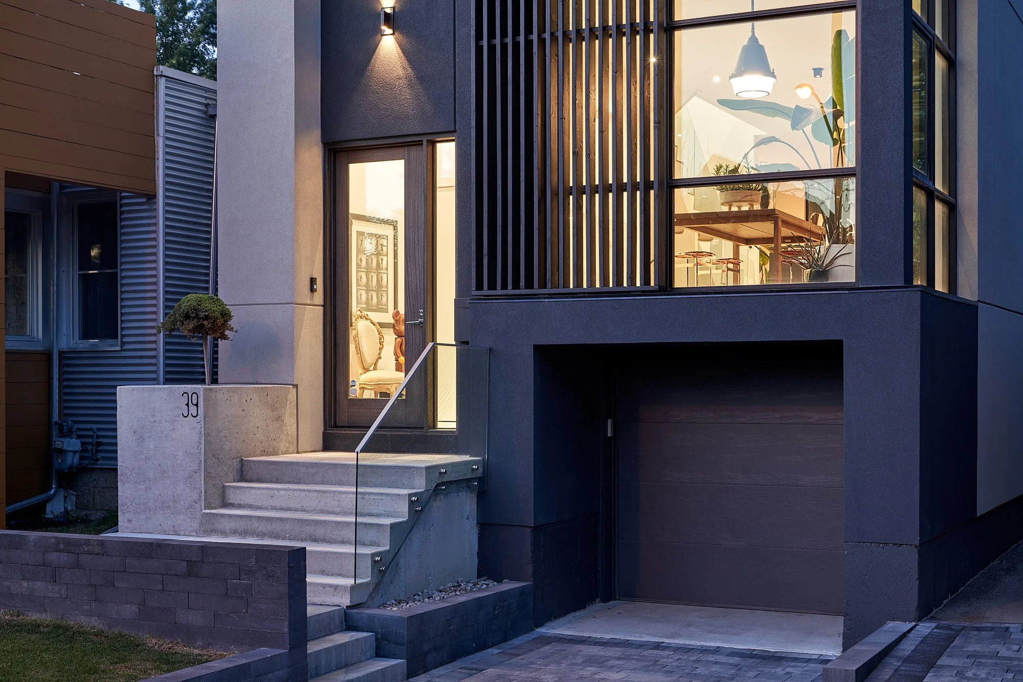 Romeo’s House exterior in Etobicoke, Toronto, built by Maxamin Homes, with concrete stairs, glass door, garage, potted tree, and modern exterior lighting.