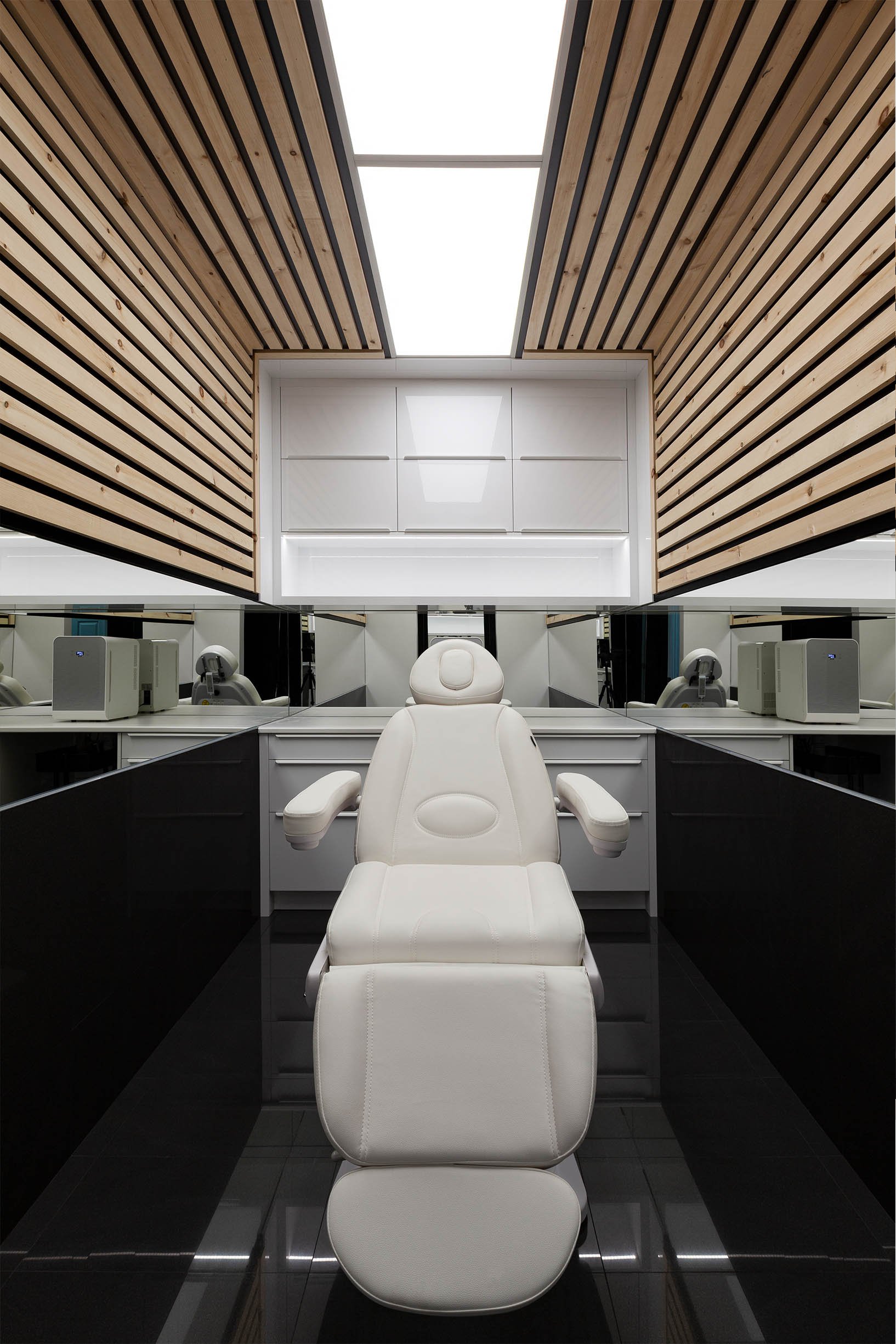 AK Clinic, a contemporary commercial renovation in Brampton, Ontario, built by Maxamin Homes with minimalist office design, wood-panel ceiling, and white ergonomic furniture.