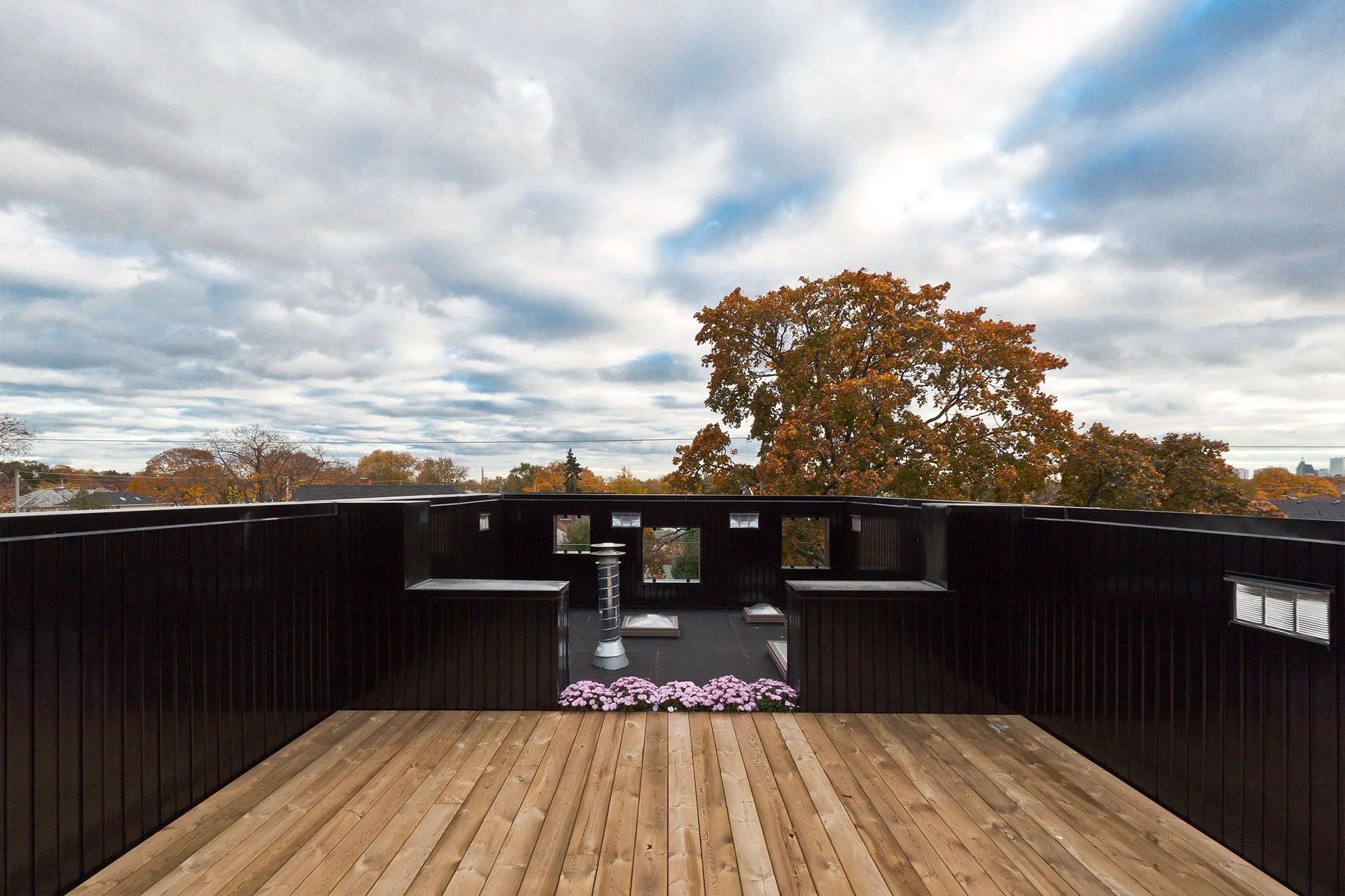 Toronto, built by Maxamin Homes, overlooking trees with autumn leaves under a partly cloudy sky.
