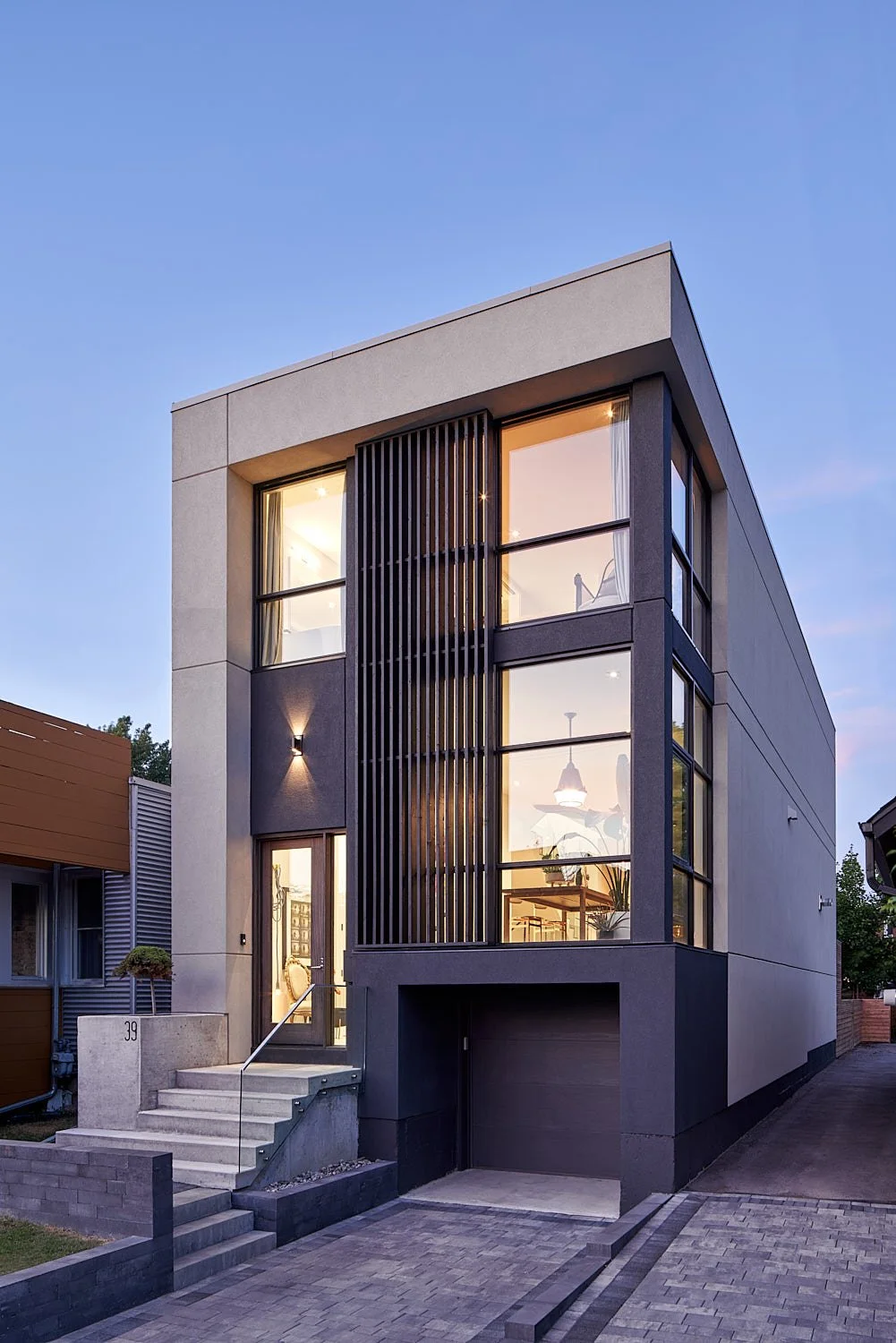 Romeo’s House, a modern three-story custom home in Etobicoke, Toronto, built by Maxamin Homes, featuring large glass windows and exterior lighting at dusk.