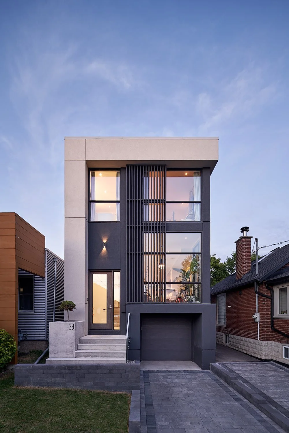 Romeo’s House, a modern multi-story custom home in Etobicoke, Toronto, built by Maxamin Homes, with large glass windows, black vertical slat façade, and front steps.