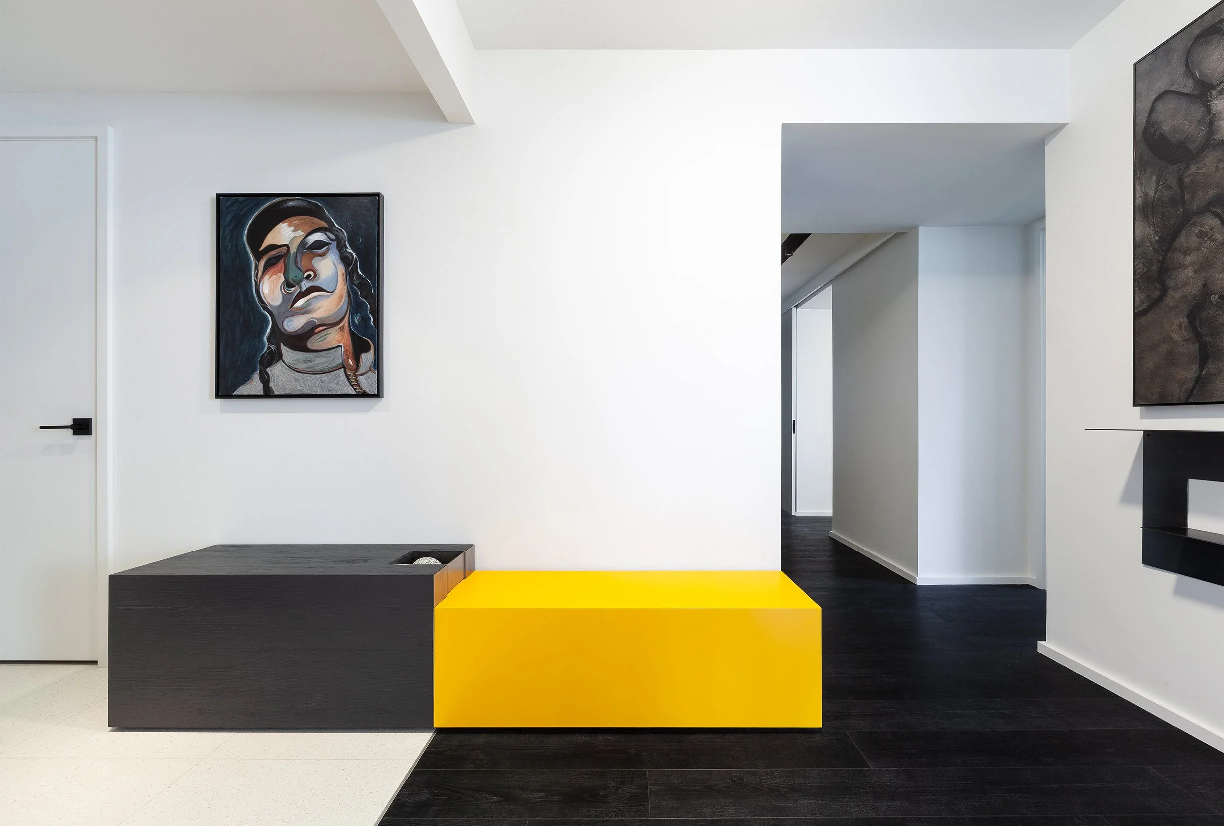 DOHA Nest interior in North York, Toronto, built by Maxamin Homes, with white walls, black and yellow benches, and contemporary art displayed on walls.