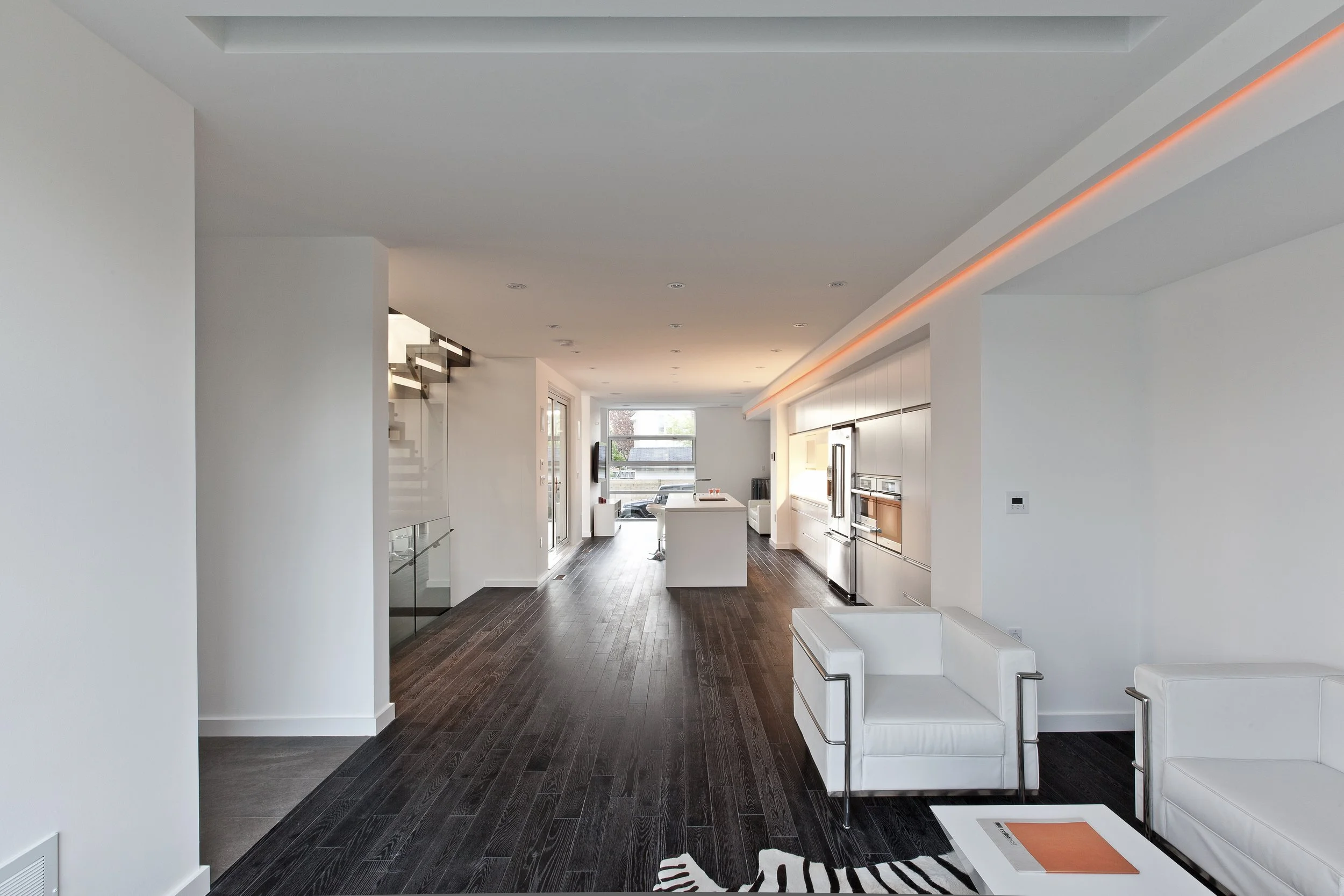 Patio House interior in North York, Toronto, built by Maxamin Homes, open-concept living area with white walls, dark floors, and modern furnishings.