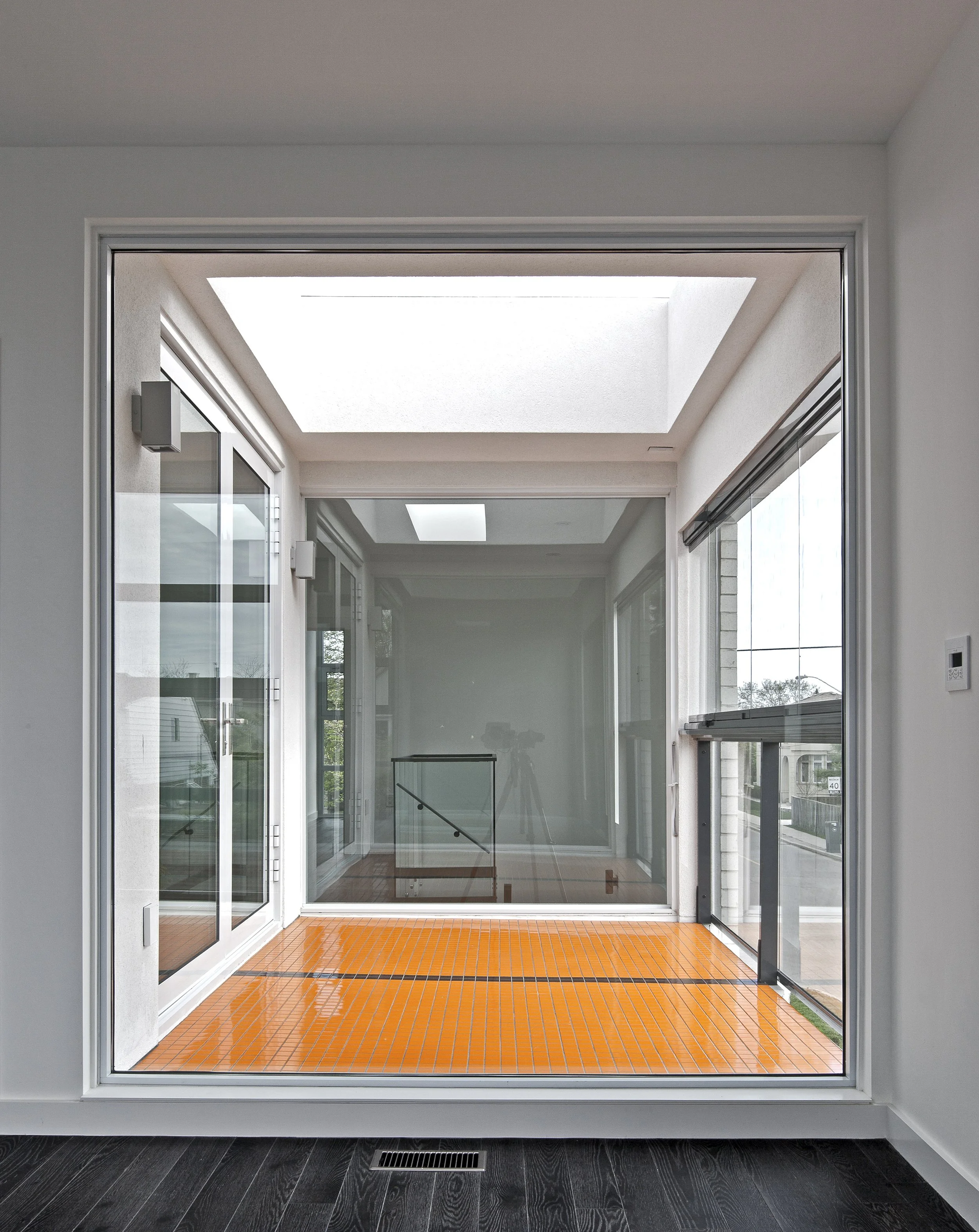 Patio House room in North York, Toronto, built by Maxamin Homes, with large glass windows, orange tile floor, and view of street outside.