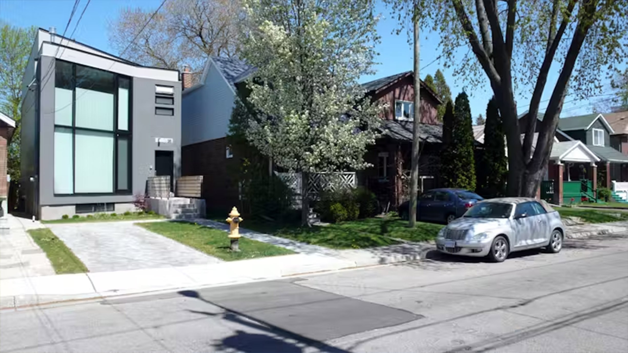 63˚ House, a modern two-story custom home in East York, Toronto, built by Maxamin Homes, featuring gray exterior, large windows, black front door, and paved walkway.