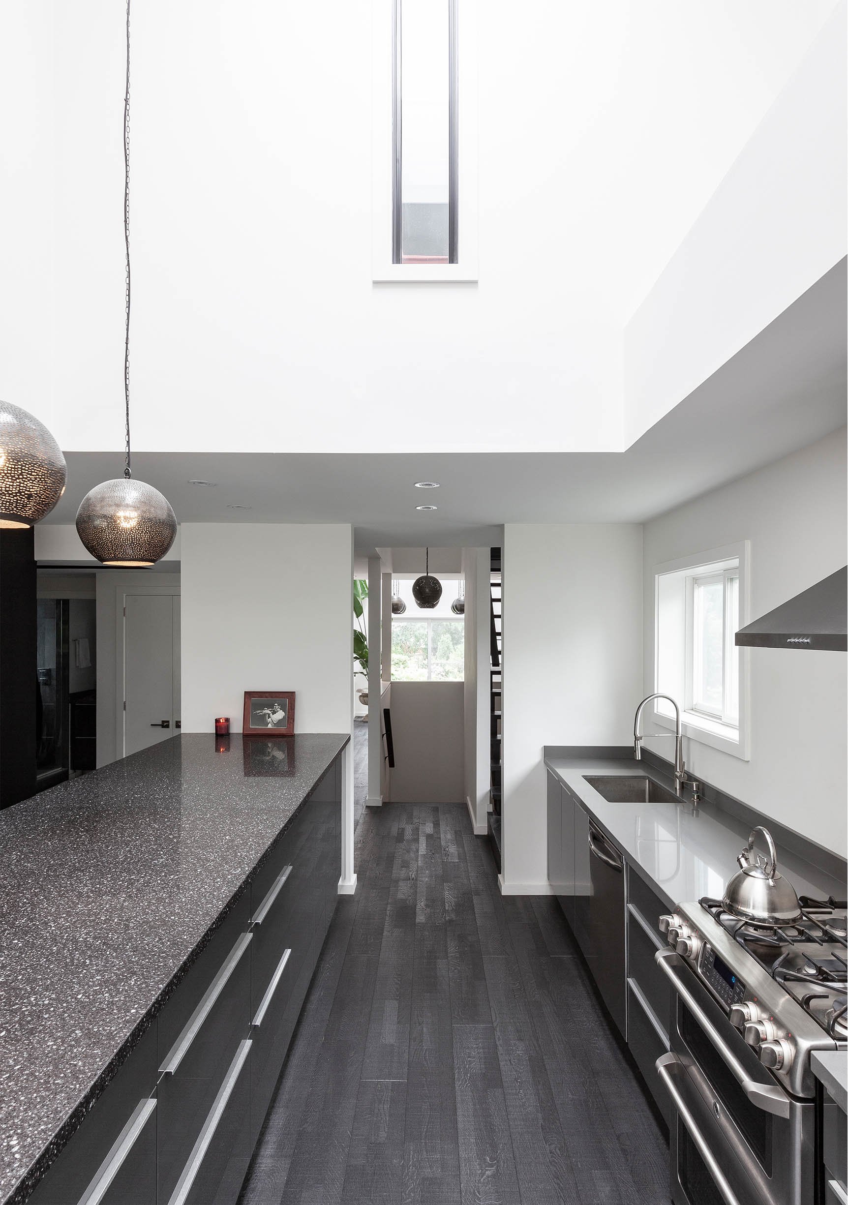Ebenos House, a modern kitchen in North York, Toronto, featuring dark cabinets, granite countertops, stainless steel appliances, and white walls built by Maxamin Homes.