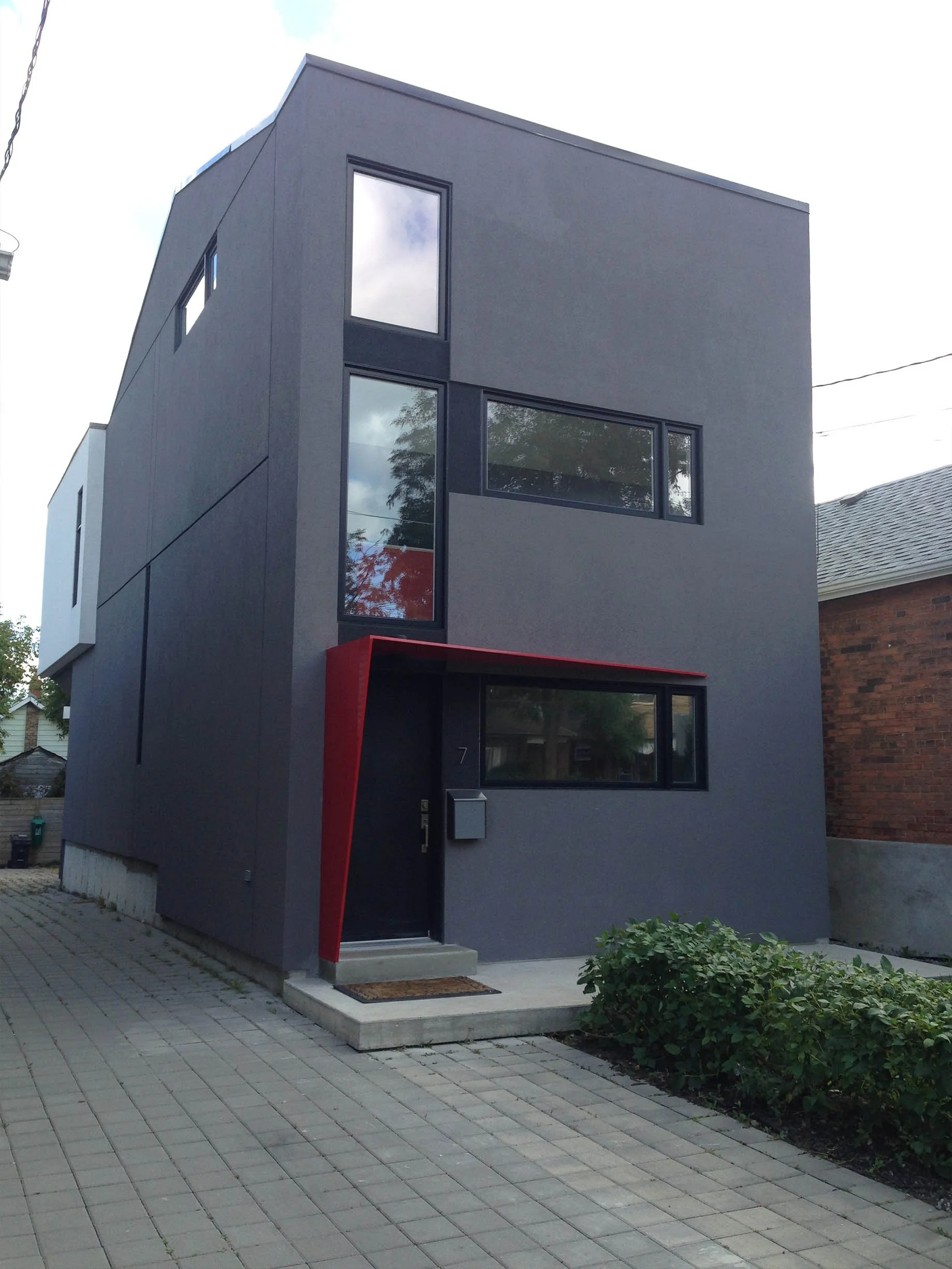 Whale House exterior in East York, Toronto, built by Maxamin Homes, gray three-story design with black windows and red accent above entrance.