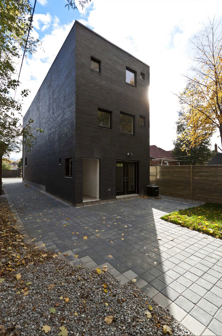 Charcoal House, a modern black multi-story custom home in East York, Toronto, built by Maxamin Homes, with square windows and small front yard.