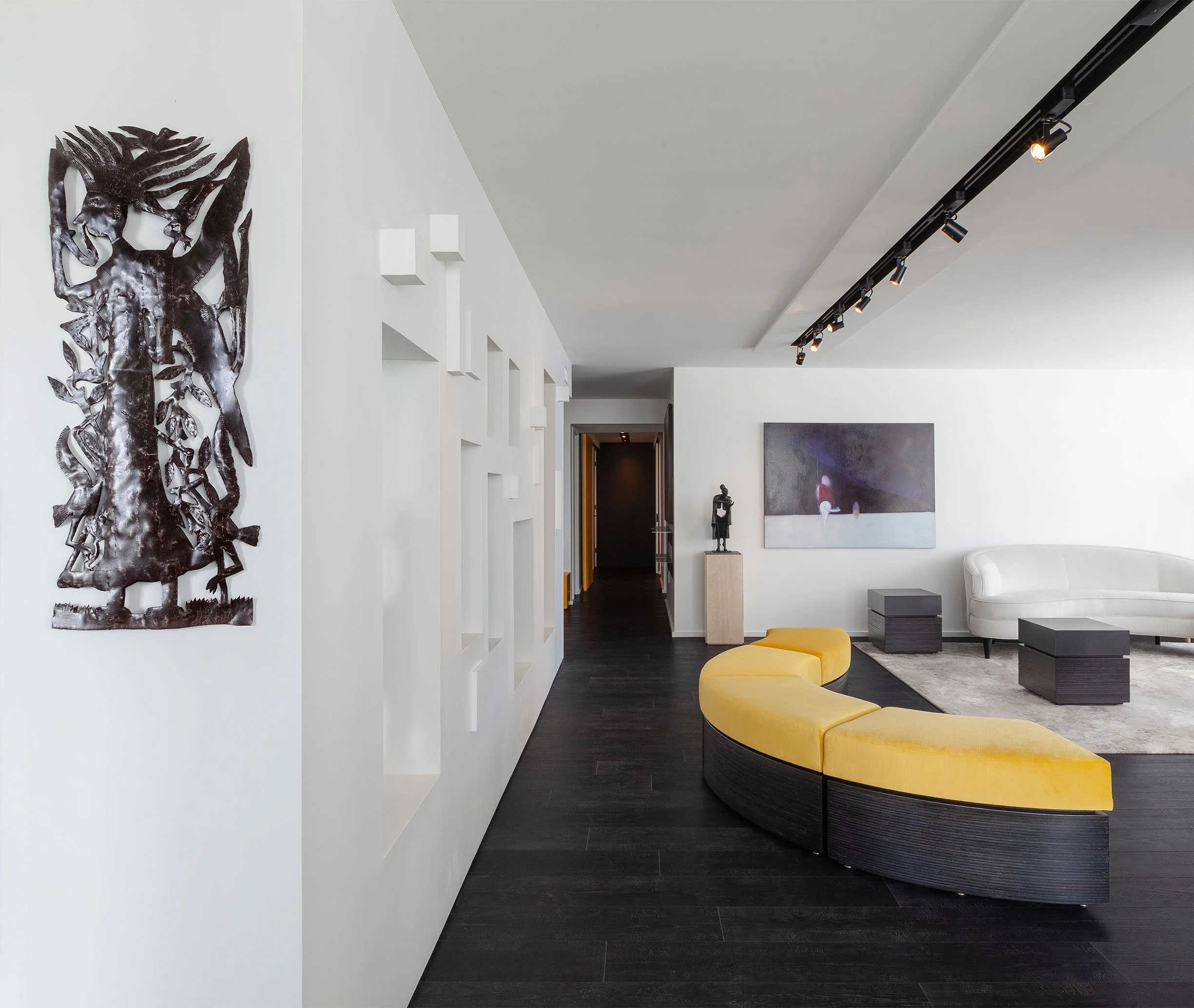 DOHA Nest living room in North York, Toronto, built by Maxamin Homes, featuring white walls, black floors, yellow curved sofa, and modern wall art.
