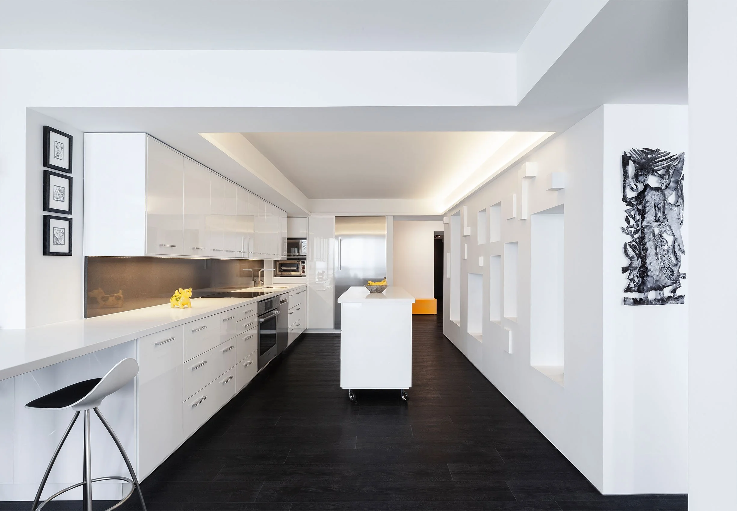 DOHA Nest, a modern luxury home renovation in North York, Toronto, built by Maxamin Homes, featuring a minimalist white kitchen with black flooring, central island, wall-mounted cabinets, and abstract artwork.