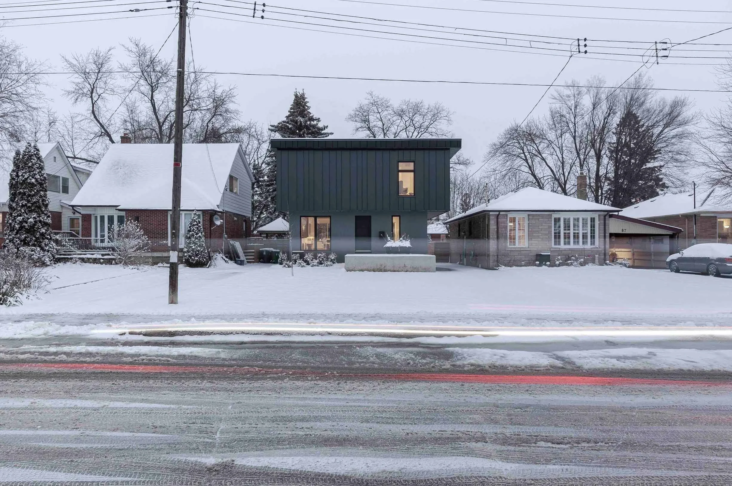 Street view near Albers House in Scarborough, Toronto, showing snowy neighborhood with three houses, trees, utility pole, and parked car.