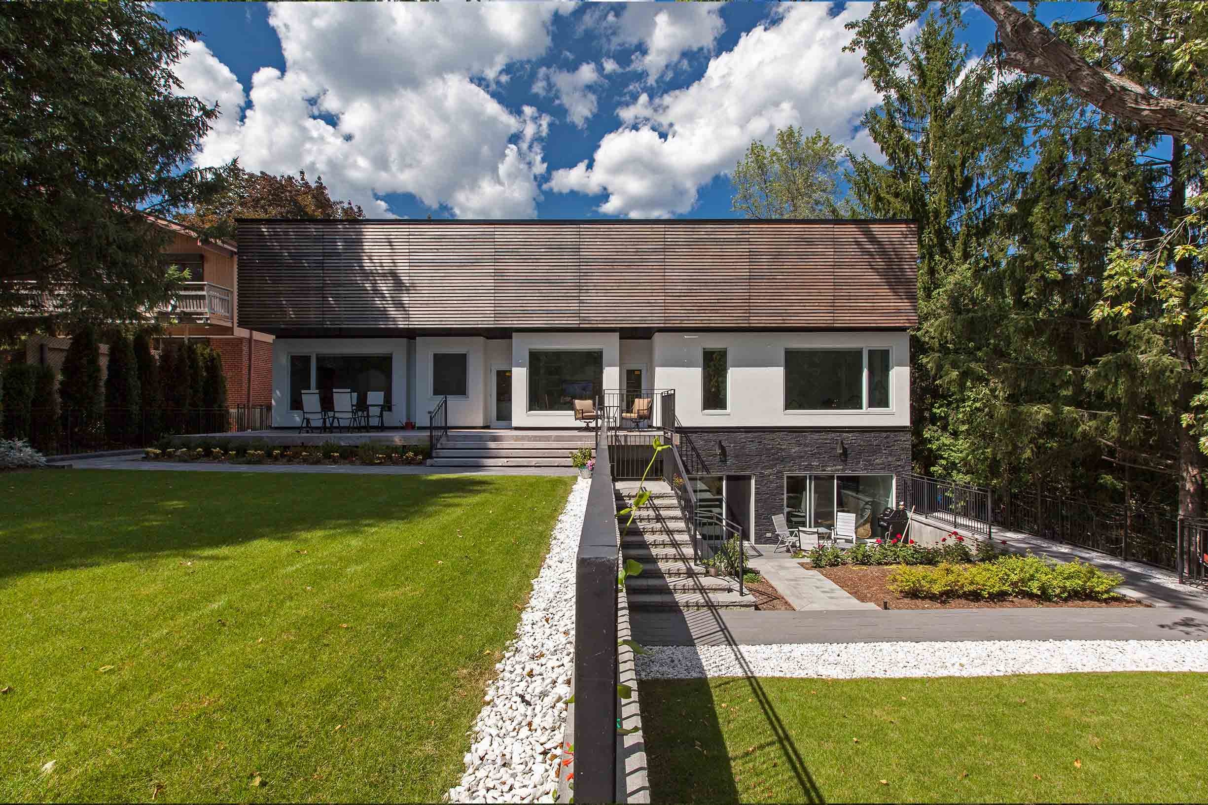 Gallery House, a modern luxury custom home in East York, Toronto, built by Maxamin Homes, featuring a two-story design with large windows, a landscaped lawn, and outdoor sitting areas that highlight architectural minimalism and refined living.