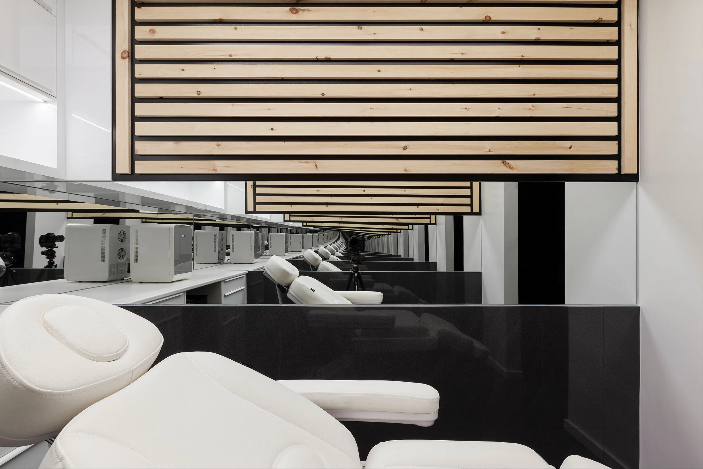 AK Clinic salon area in Brampton, Toronto, built by Maxamin Homes, with white chairs, mirror walls, computer stations, and wood ceiling panels.
