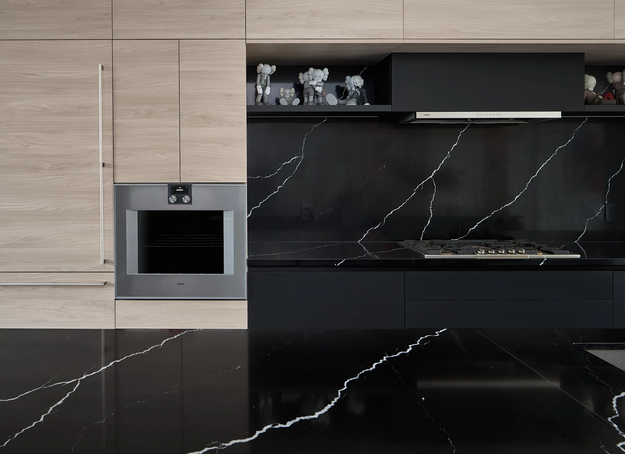 Romeo’s House kitchen in Etobicoke, Toronto, built by Maxamin Homes, featuring light wood cabinets, black marble backsplash, and matching marble flooring.