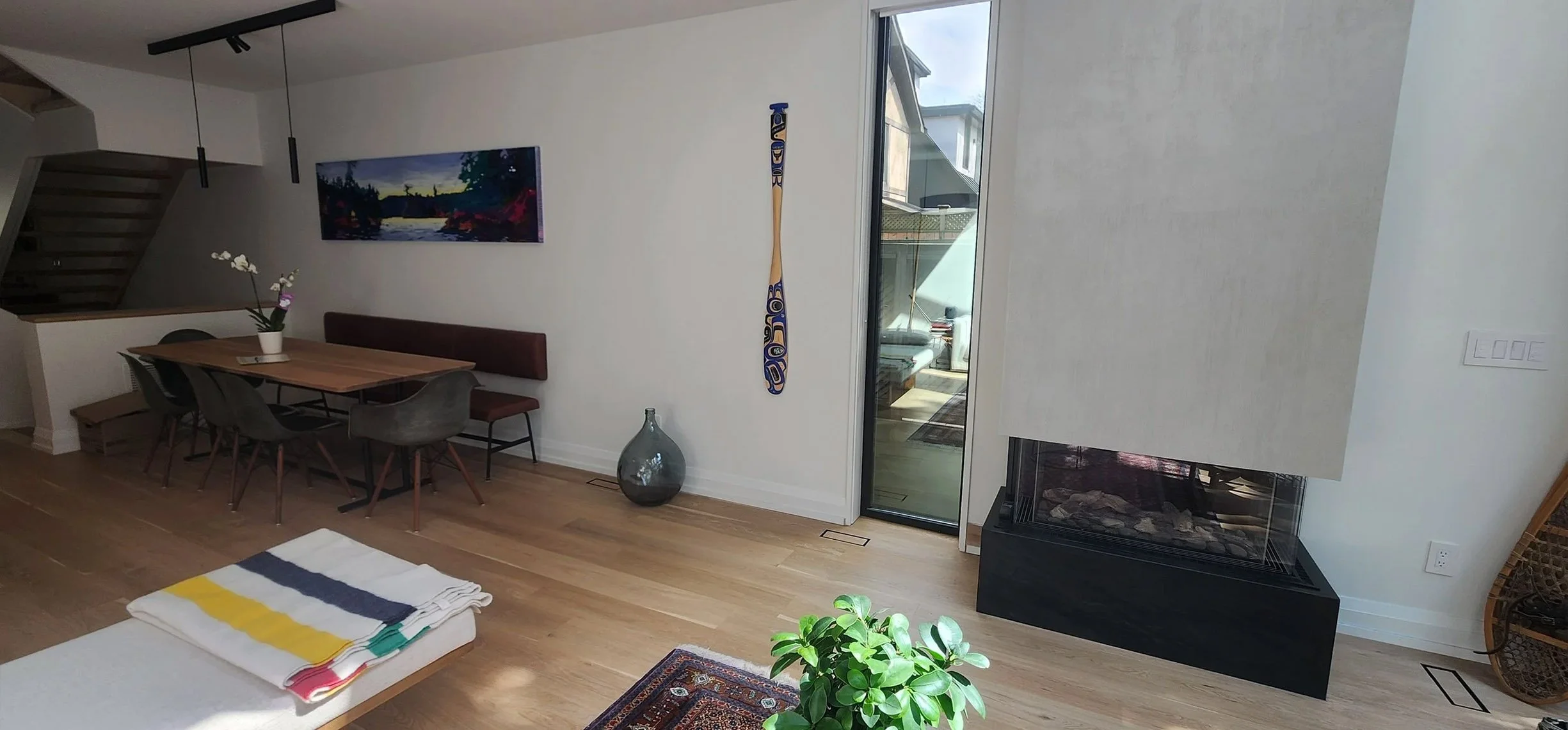 Lantern House interior in The Beaches, Toronto, built by Maxamin Homes, with dining area, guitar wall art, fireplace, and doors to outdoor patio.