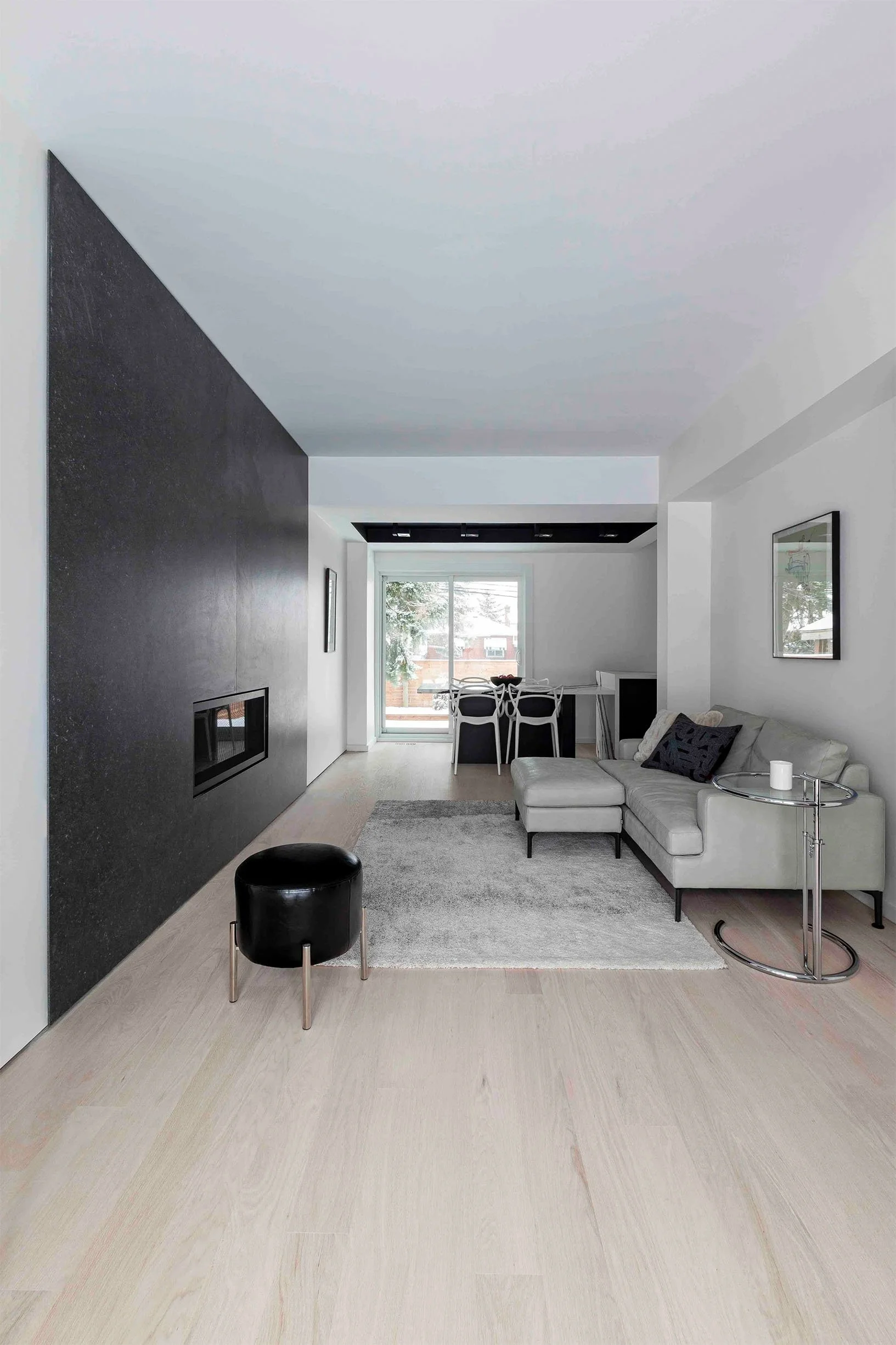 Albers House living room in Scarborough, Toronto, built by Maxamin Homes, with white sofa, black accent wall, dining area, and sliding glass door.