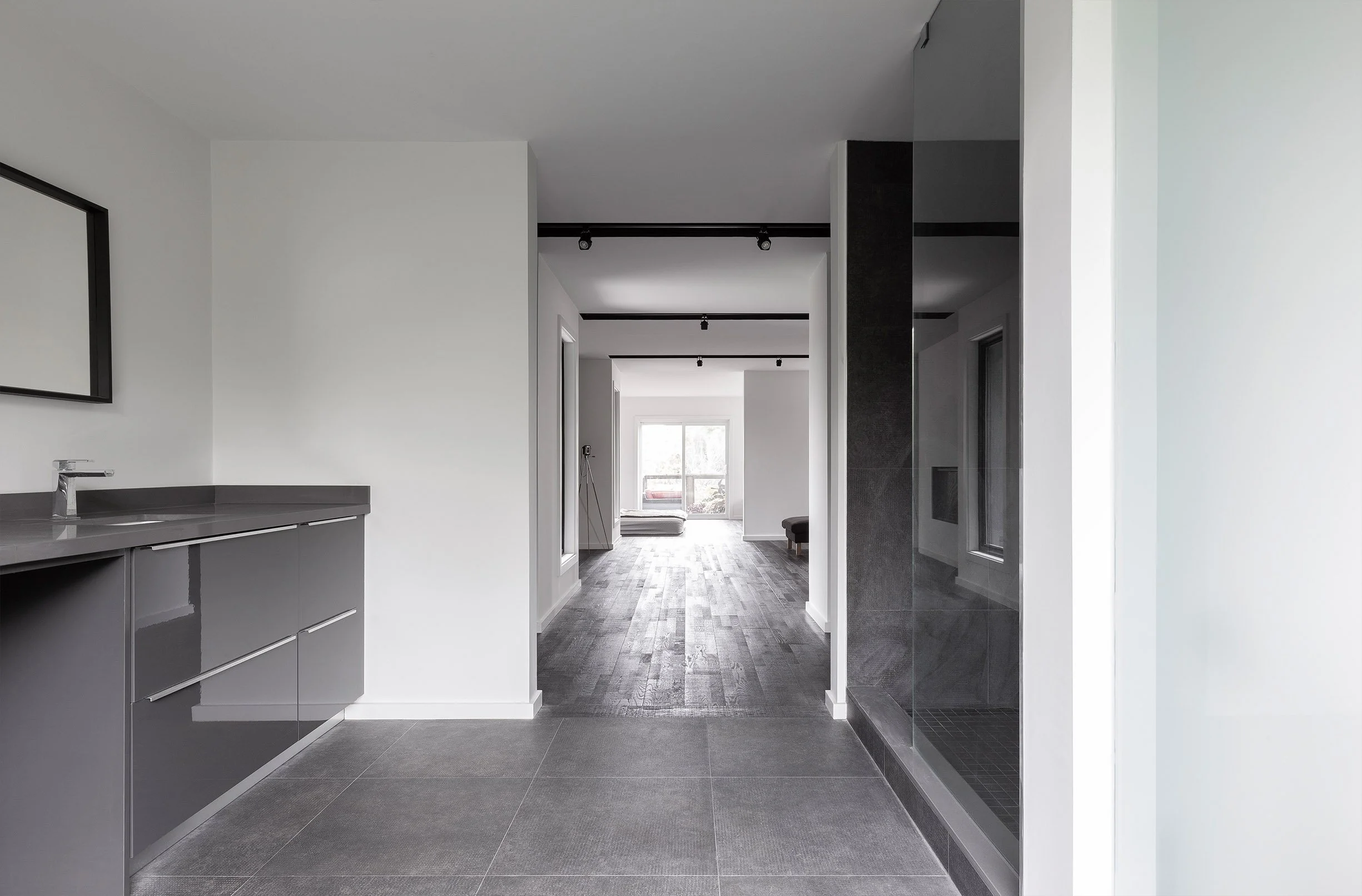 Ebenos House, an open-concept suite in North York, Toronto, with gray cabinetry, glass-enclosed shower, and wood flooring leading to large windows built by Maxamin Homes.
