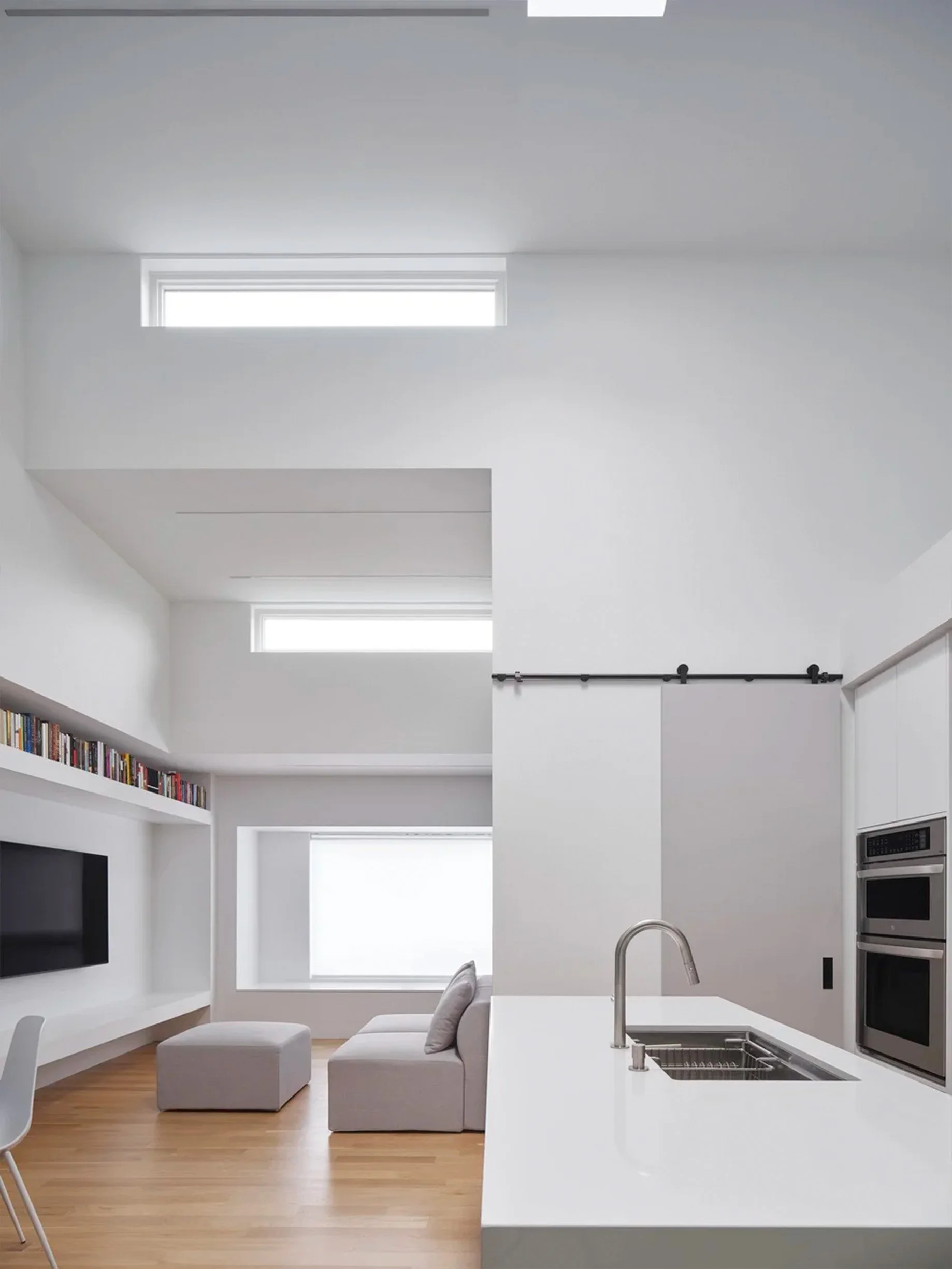 Periscope House interior in East York, Toronto, built by Maxamin Homes, minimalist living area with kitchen, white walls, and high windows for light.