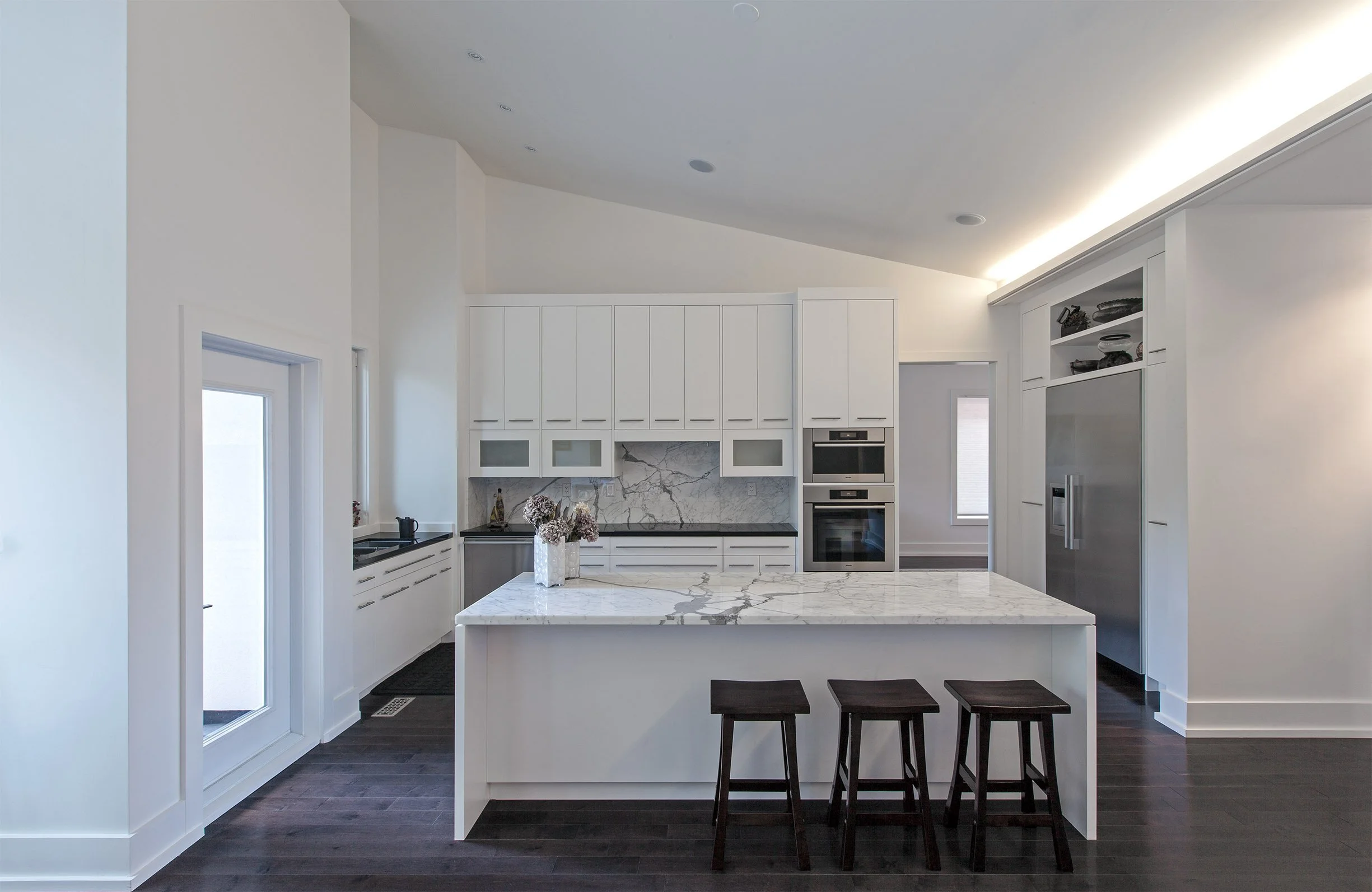 Gallery House kitchen in East York, Toronto, built by Maxamin Homes, featuring marble island, white cabinetry, dark wood floors, and built-in appliances.