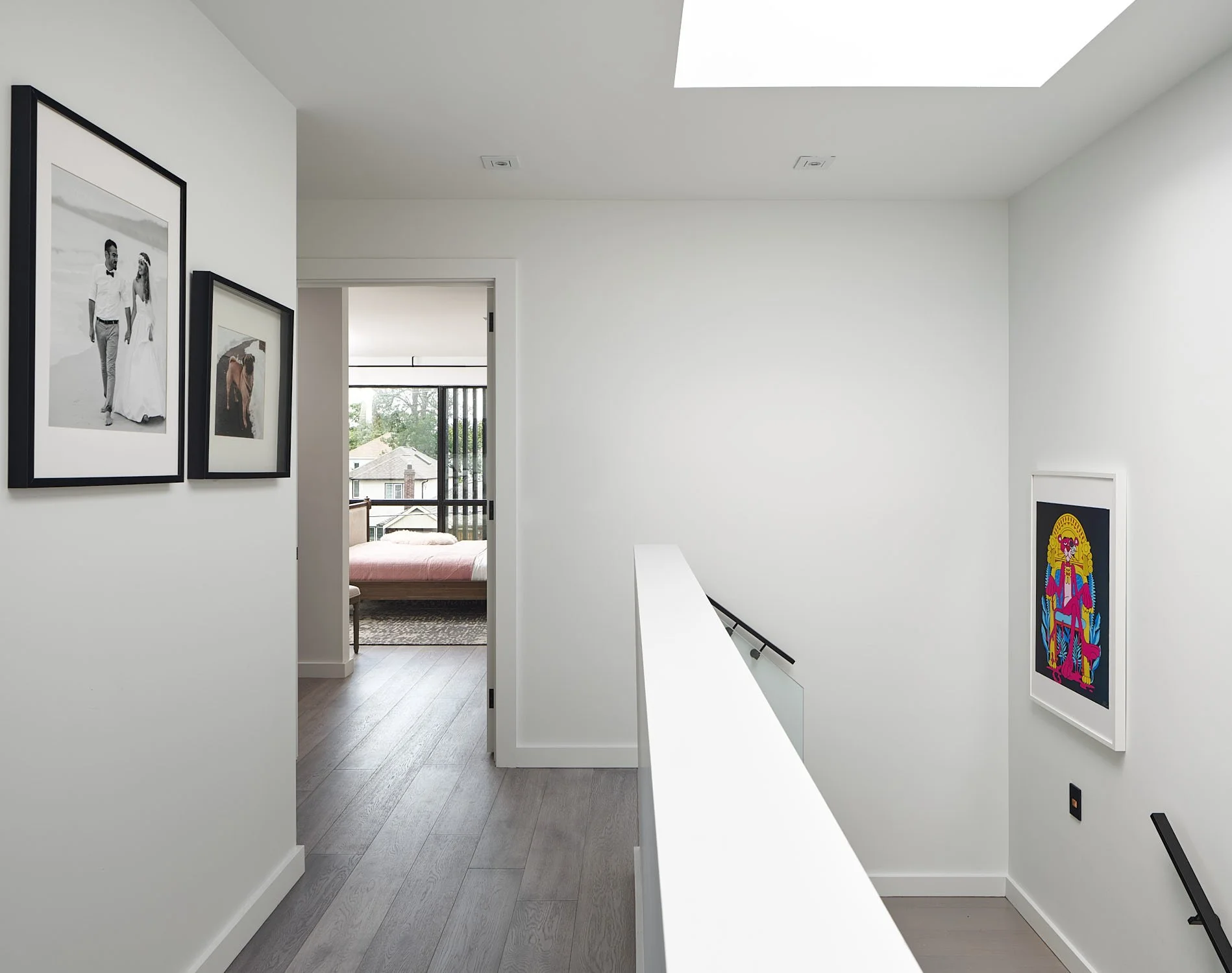 Romeo’s House hallway in Etobicoke, Toronto, built by Maxamin Homes, with framed photographs, colorful artwork, and a view leading to a bedroom and balcony.