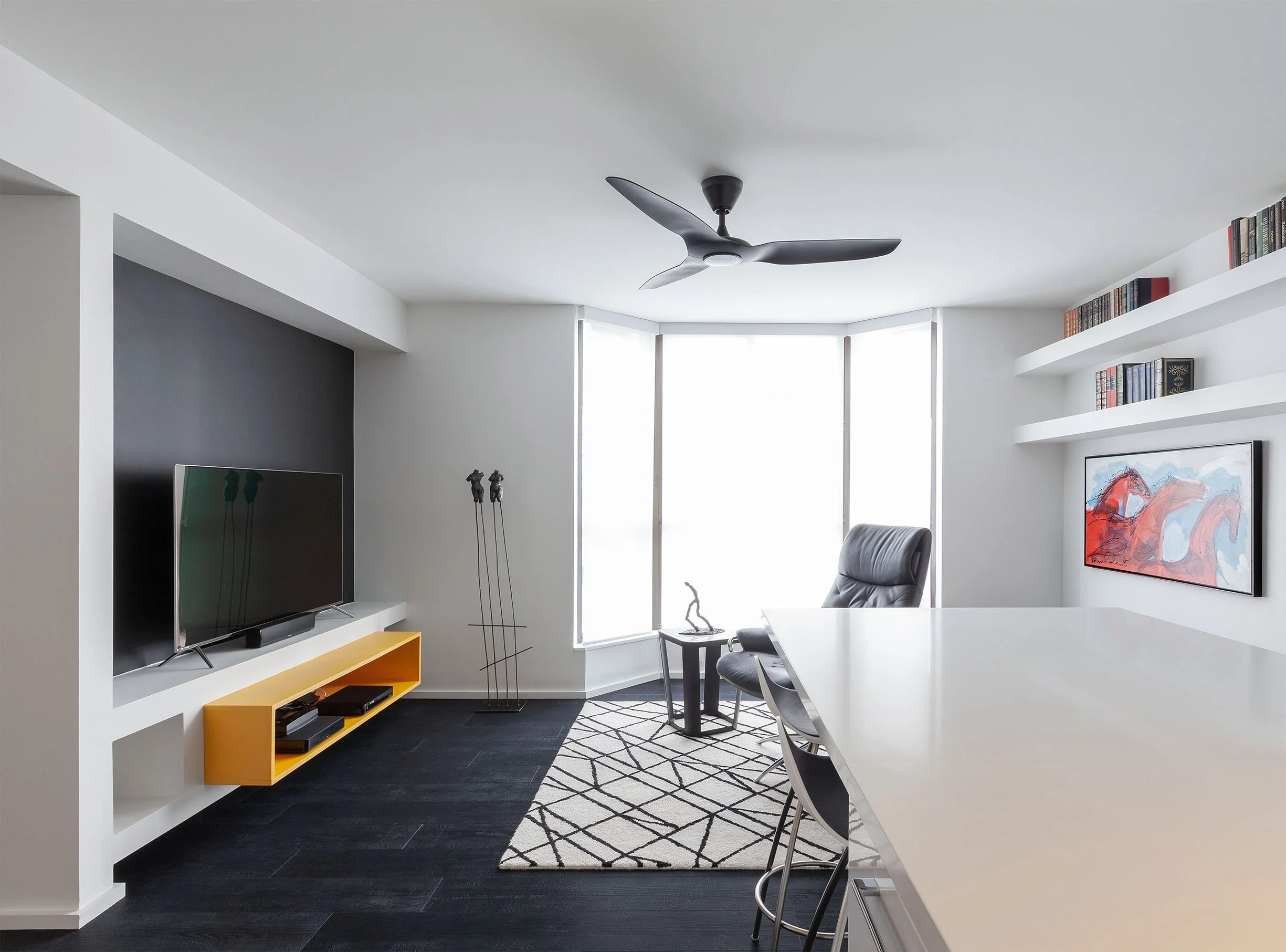 DOHA Nest living room in North York, Toronto, built by Maxamin Homes, featuring large windows, yellow TV stand, black flooring, and built-in bookshelves.