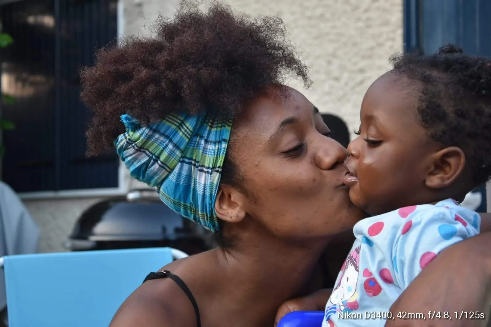 Une femme et un enfant partagent un baiser de lèvres dans une embrassade affectueuse.