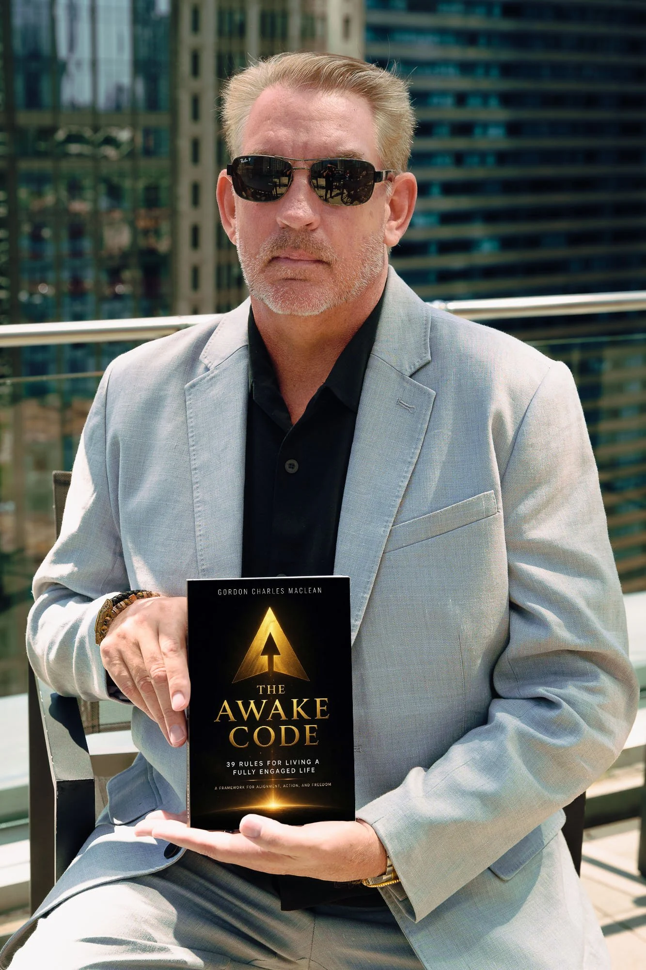 Author Gordon Charles MacLean holding his book The Awake Code