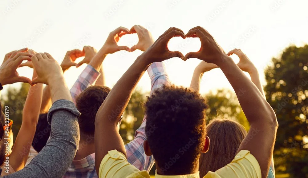 Diversity of people with hands above their arms lifted forming a heart shape with their hands