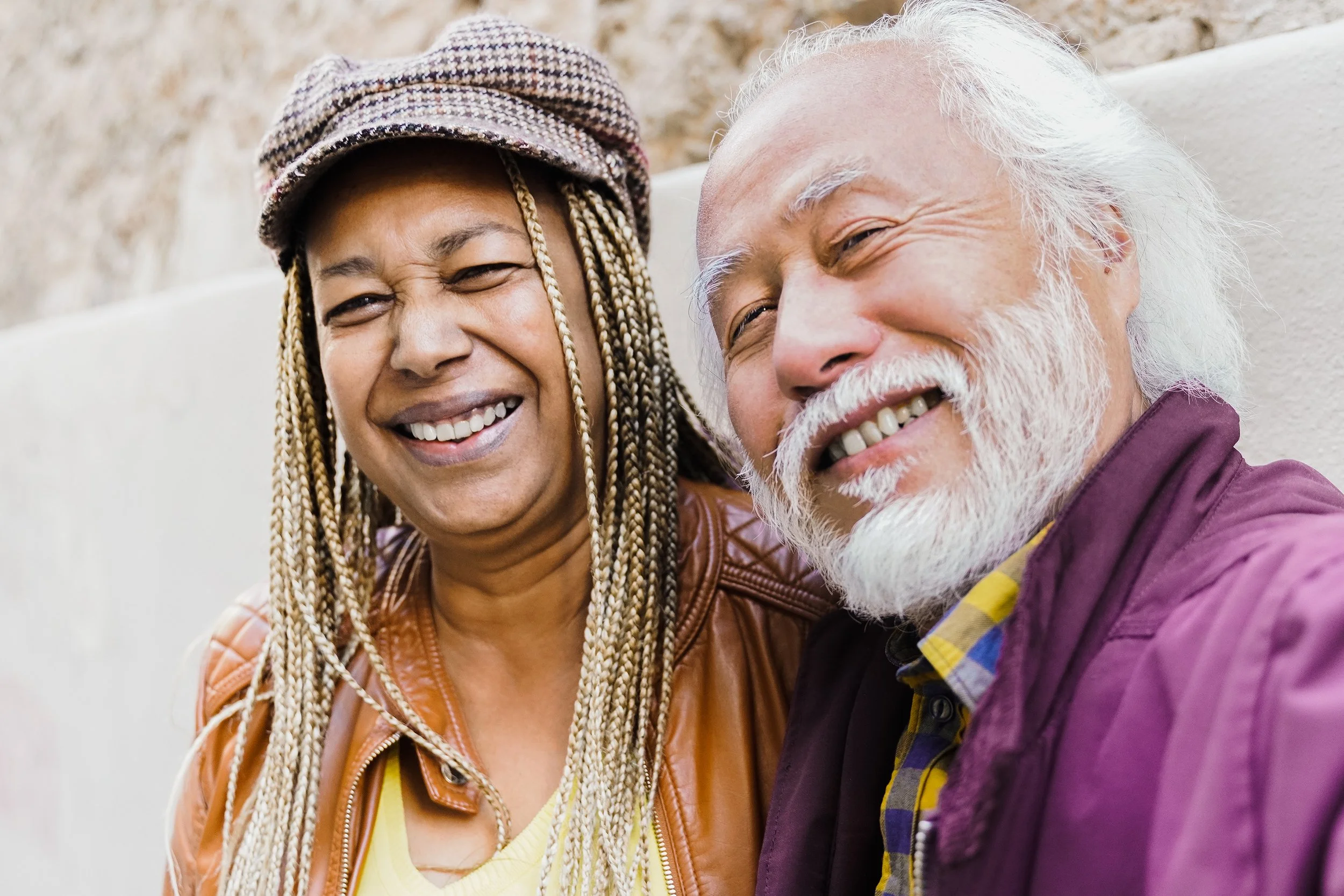 Two older adults next to one another smiling.