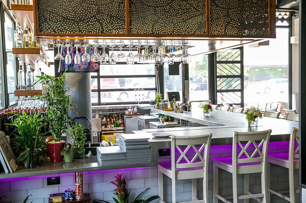 Modern bar interior with hanging glasses and purple underlighting