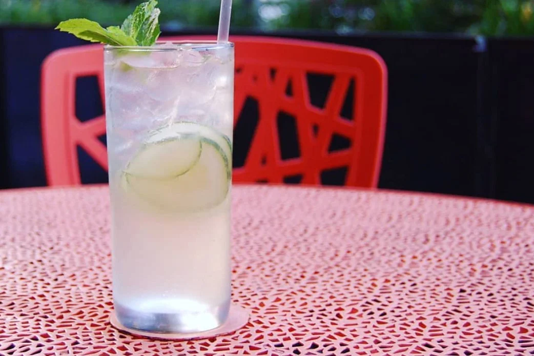 Refreshing cocktail with cucumber and mint on an orange patterned table