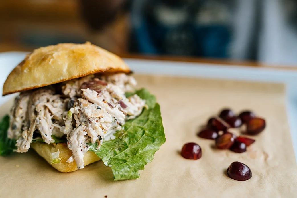 Chicken salad sandwich with grapes on a tray at TLC Lamar Union