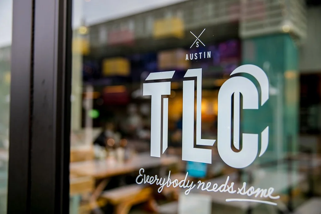 Close-up of TLC Austin logo on a restaurant window at Lamar Union