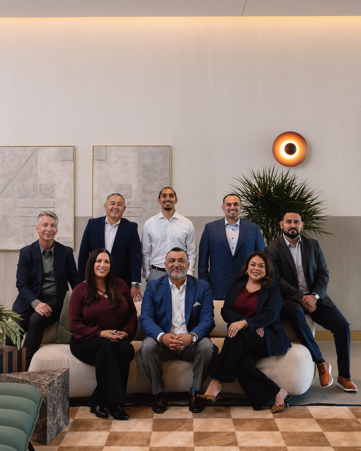 Group of nine diverse professionals posing in a modern lobby