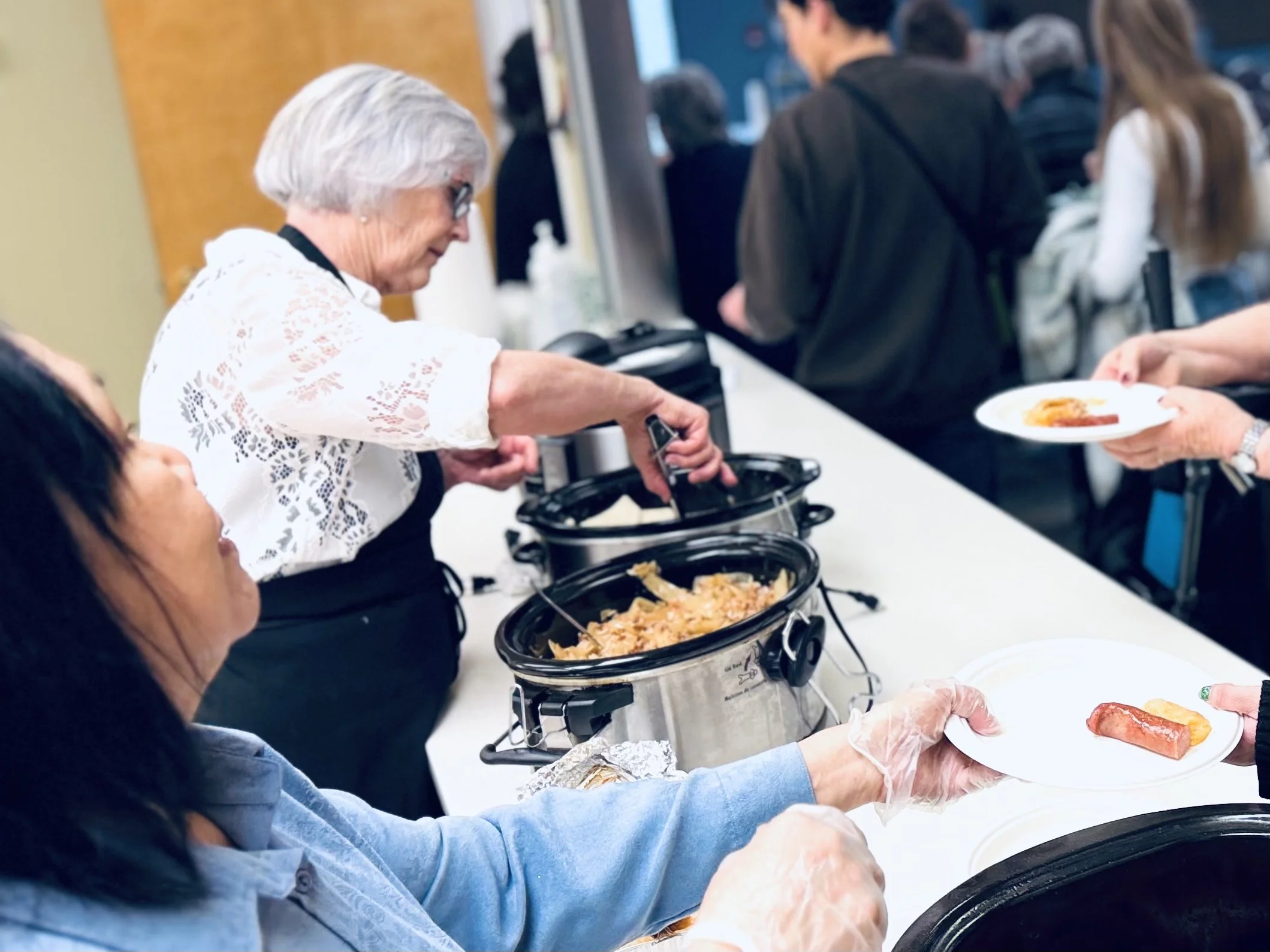 People serving and receiving food at a buffet-style meal.