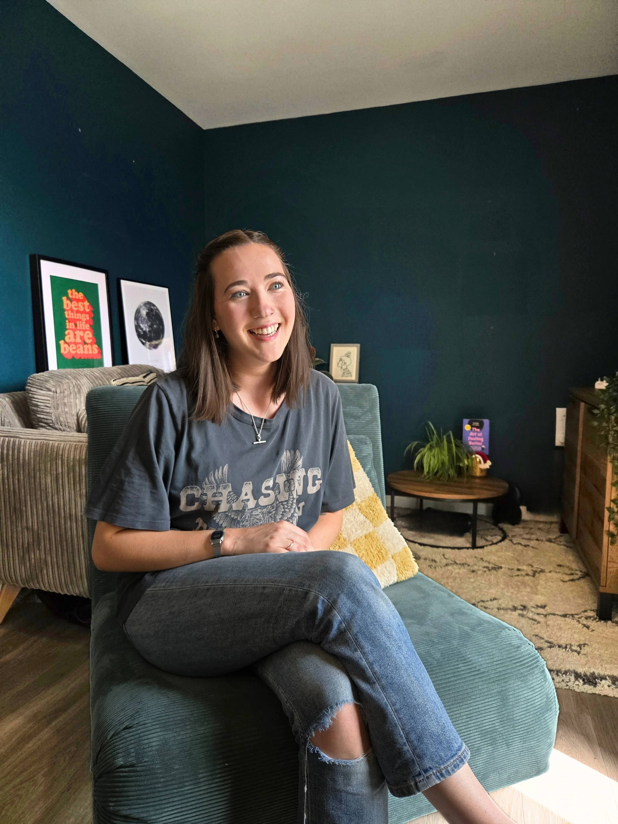 A photo of a woman smiling, sitting on a chair